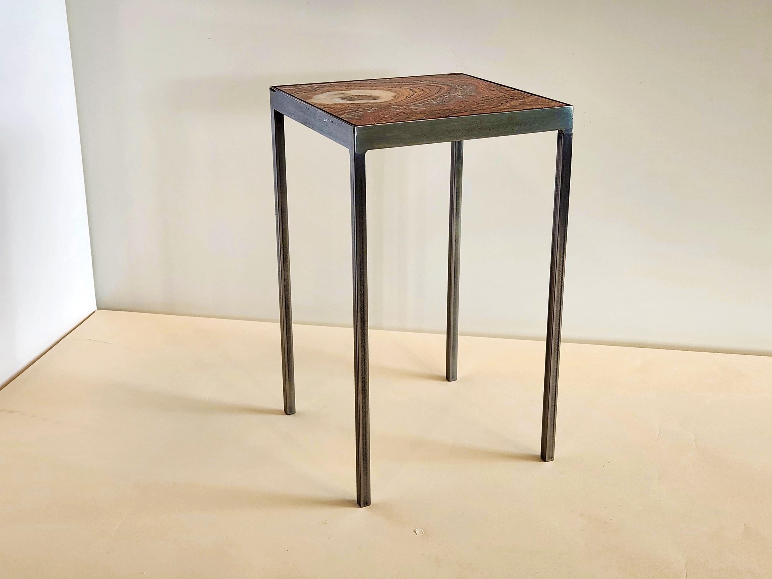 Onyx stone cut from a rare red slab showing many layers of colored sediments naturally created over millions of years by Mother Earth. The stone is set in a steel frame similar to our baby side tables with Capron tiles. With a 10