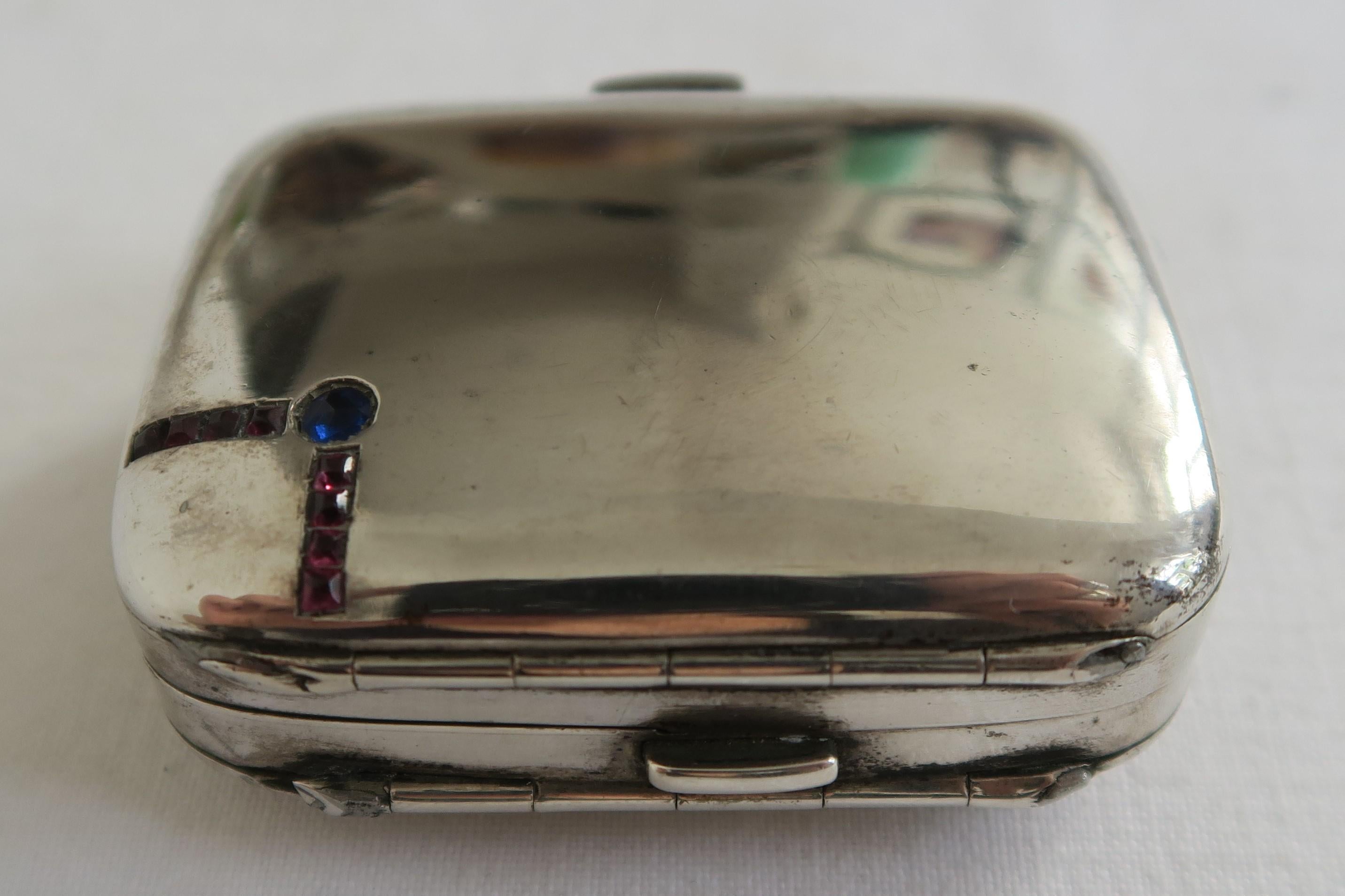 For sale is an elegant bejeweled etui. It is four times foldable with three little spring clasps, made from solid 800/1000 silver in a suitcase shape. Its lid and the backside of the box are simple polished silver, but the top left corner of the lid