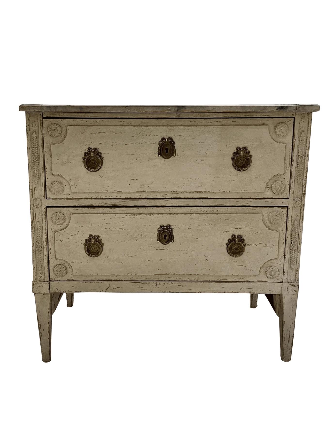 Eleganza, piccola commode svedese gustaviana della fine del XVIII secolo con dettagli classici neoclassici e vernice color crema antico. Dispone di due cassetti profondi con scudi originali in ottone ormolu e tiretti ad anello, incorniciati da