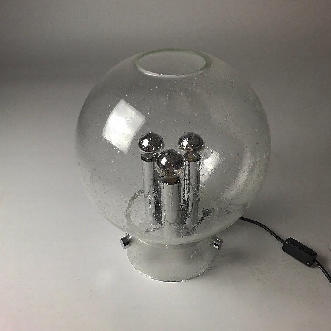 Renowned glass maker Glashütte Limburg made this beautiful stylish table lamp in the 1970s. 

Made from thick clear glass with bubbles inside which makes it look like rain covering the window. 

Looks very sculptural with the sphere, the pockets