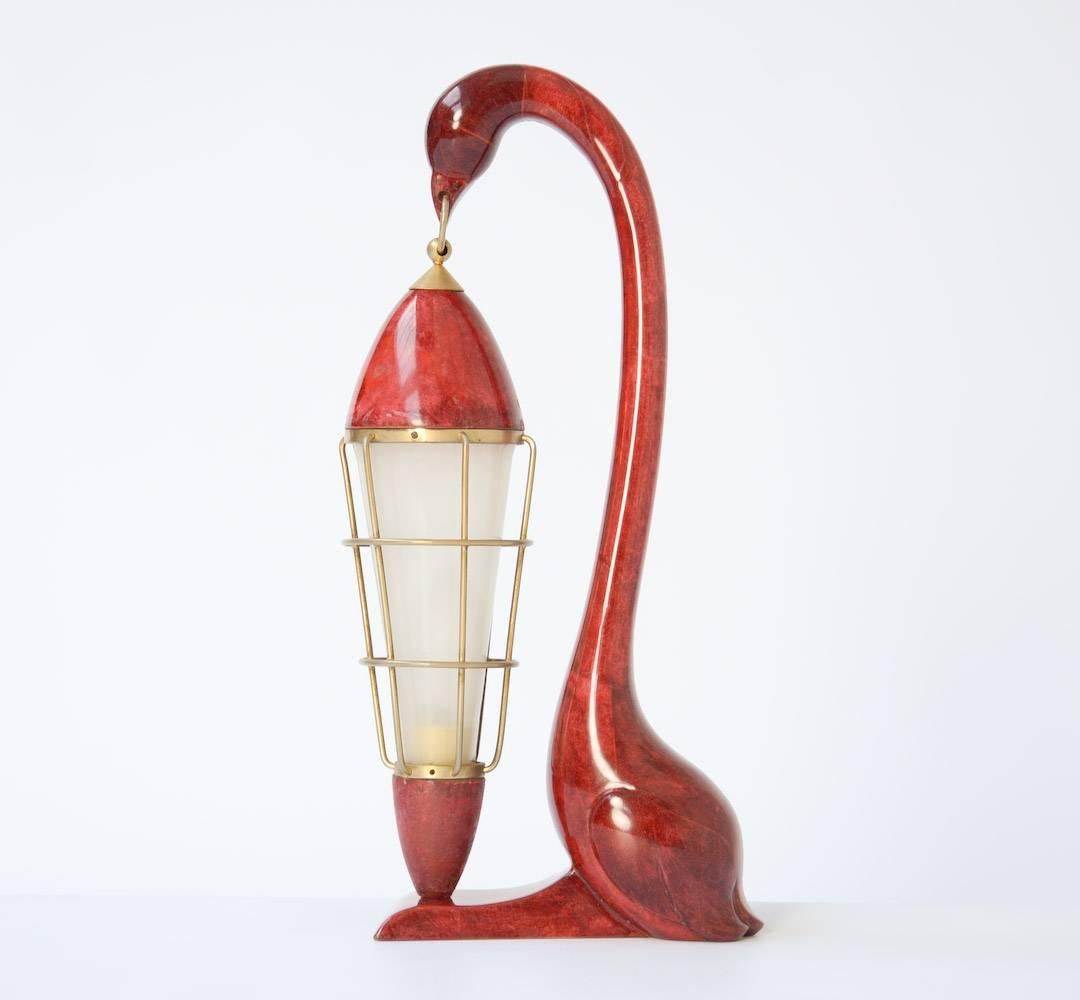 This elegant swan table lamp was designed by Aldo Tura, it can be dated in the 1950s.
The wooden swan sculpture is covered with wine-colored goatskin. The swan holds a lantern with gold-plated brass mounts and a frosted laminate inset shade.
This