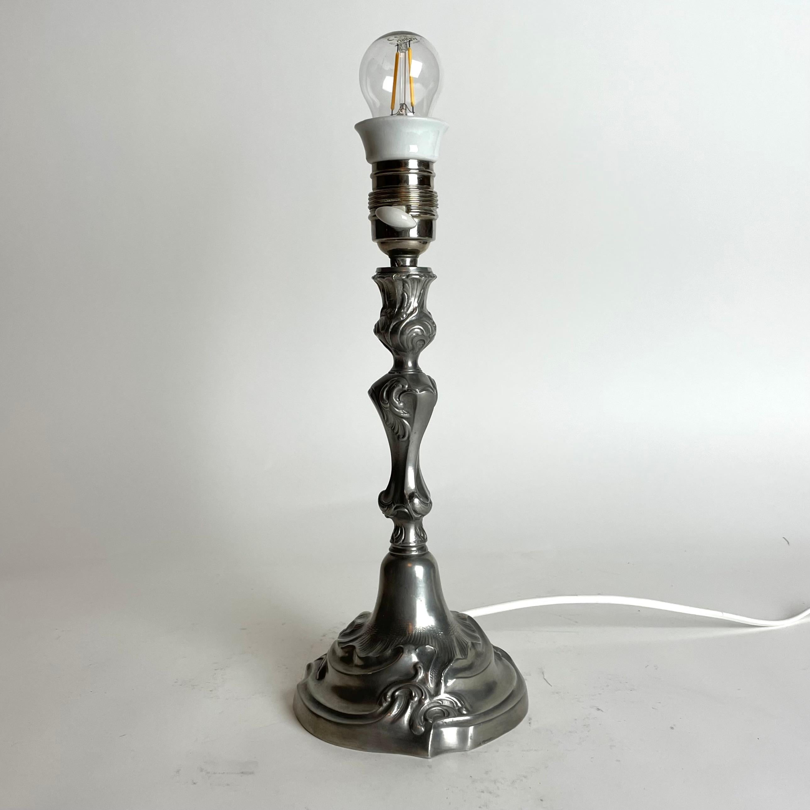 Elegant Table Lamp in pewter in Rococo style from 1938. Made in Sweden, with original lamp holder in chrome and porcelain. Newly installed electricity.

Wear consistent with age and use 