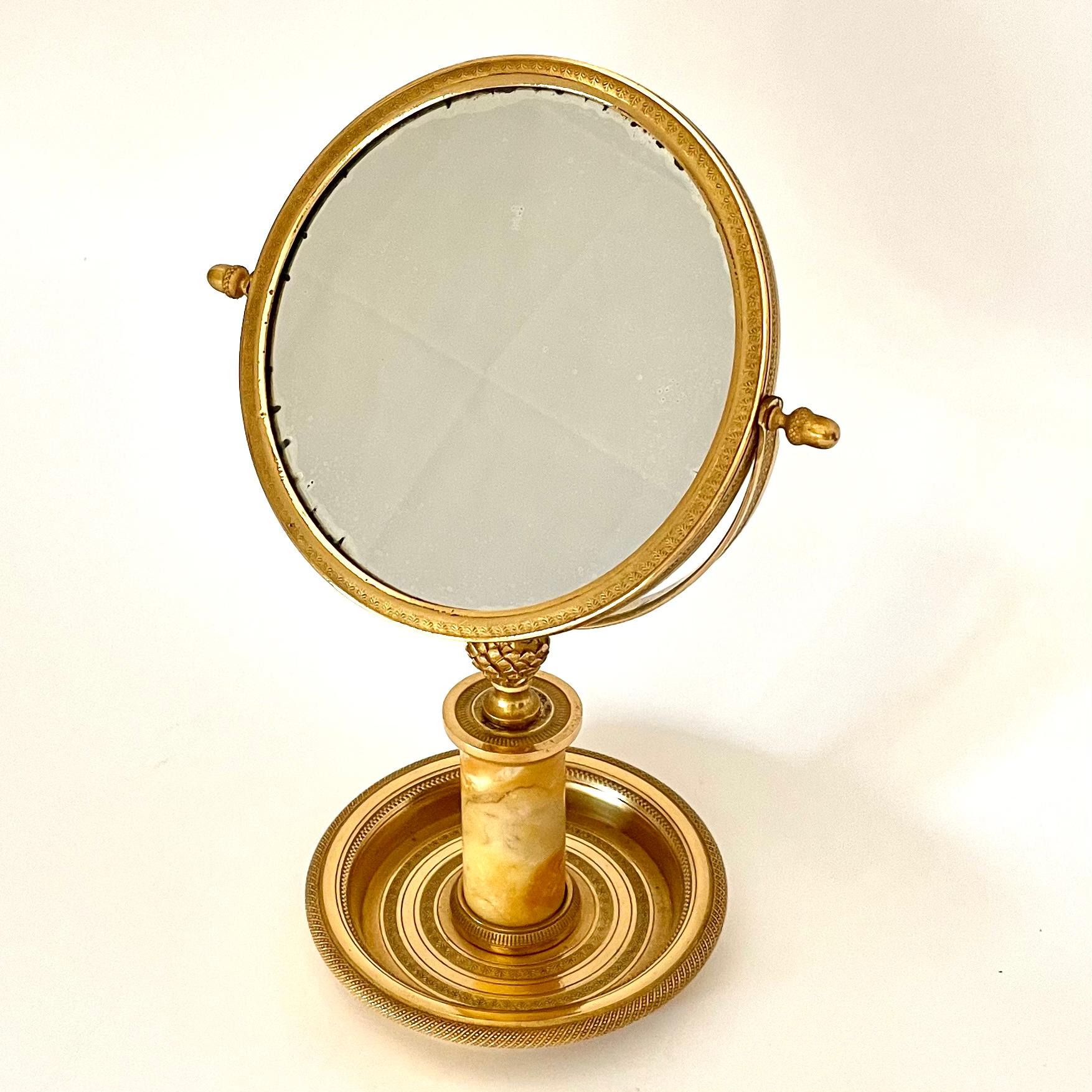 Eleganter Tischspiegel aus vergoldeter Bronze und mit einem Marmorkern. Sehr schöne Originalvergoldung mit schönen Details. Französisches Kaiserreich ab den 1820er Jahren. Gute Größe für den Schminktisch oder als schöner Spiegel im Flur.

Alters-