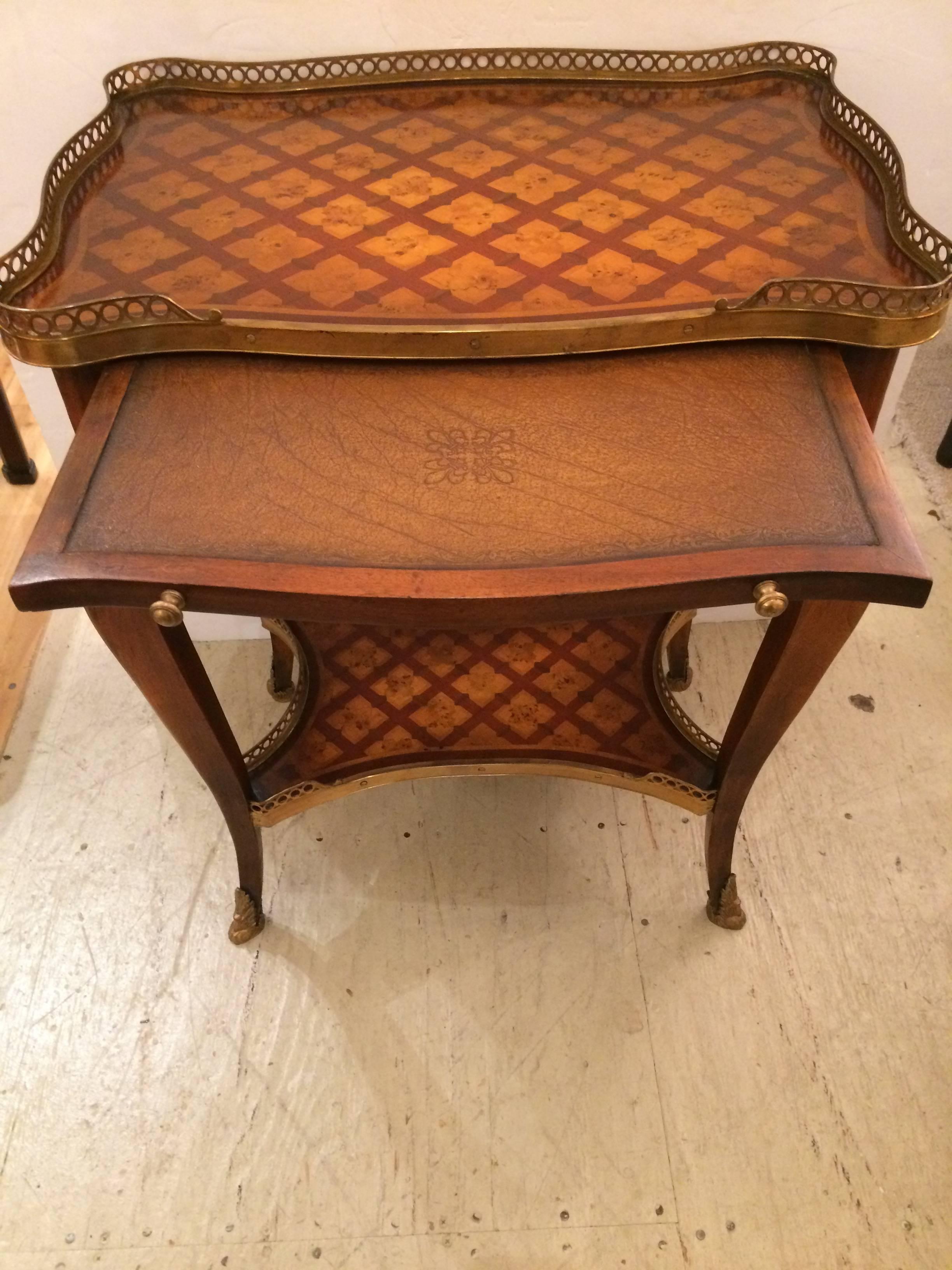 Especially beautiful two-tier side table having gorgeous inlaid wood in light and dark colors, a handsome filligree brass gallery on top and bottom, cabriole elegant legs with brass caps, and a single drawer with original hardware.
