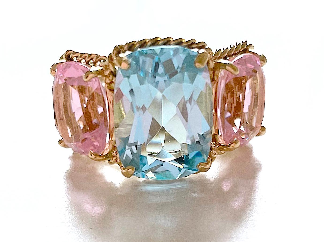 Christina Addison bespoke Elegant 18kt Yellow Three Stone Ring with Rope Twist Border with split shank detail. The ring features a center faceted cushion cut Blue Topaz and two cushion Pink Topaz stones surrounded by twisted gold rope. The center