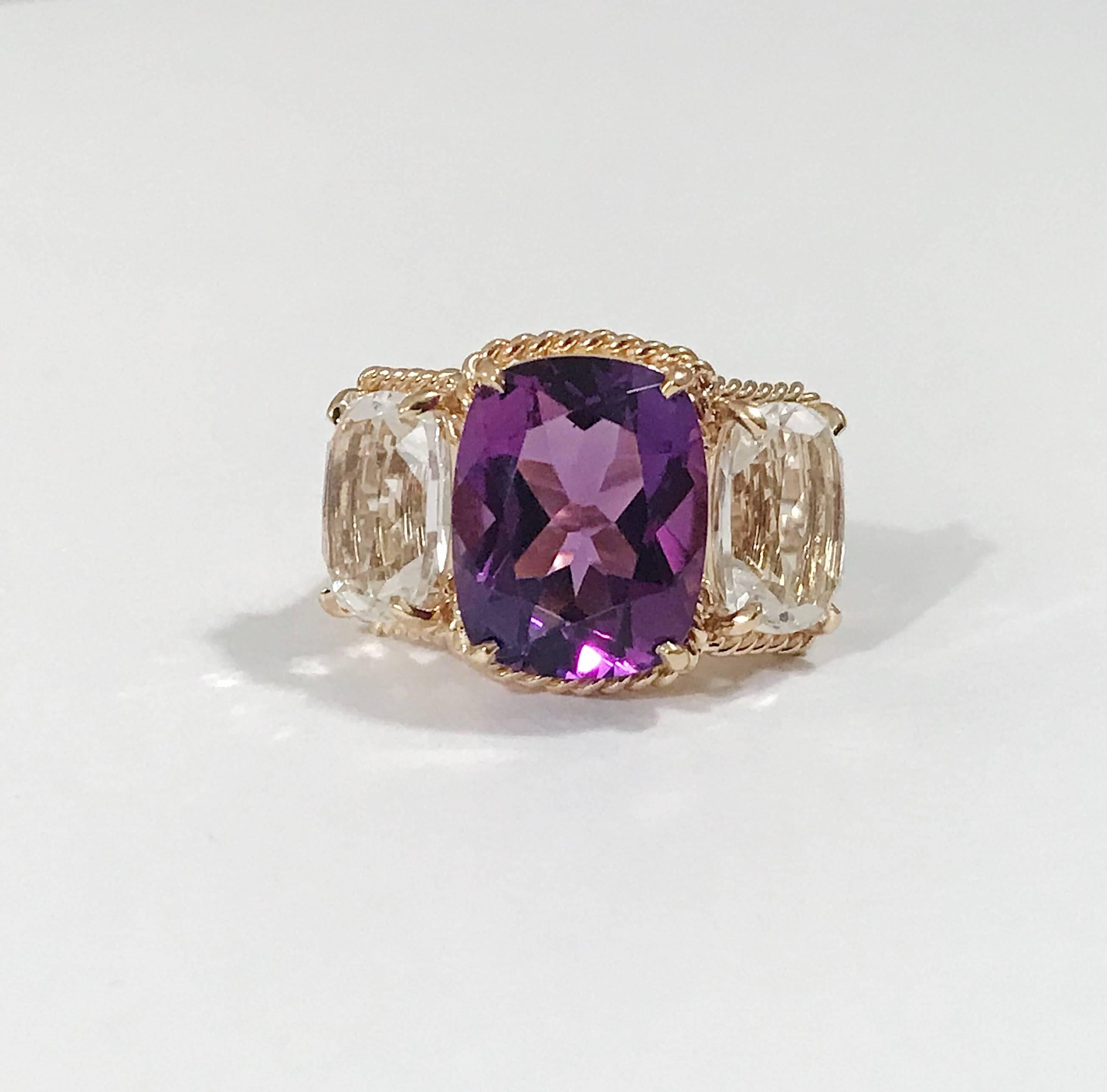 Elegant 18kt Yellow Three Stone Ring with Rope Twist Border with split shank detail.

The ring features faceted cushion cut Purple Amethyst and Rock Crystal stones surrounded by a twisted gold rope. The center Amethyst measures 5/8