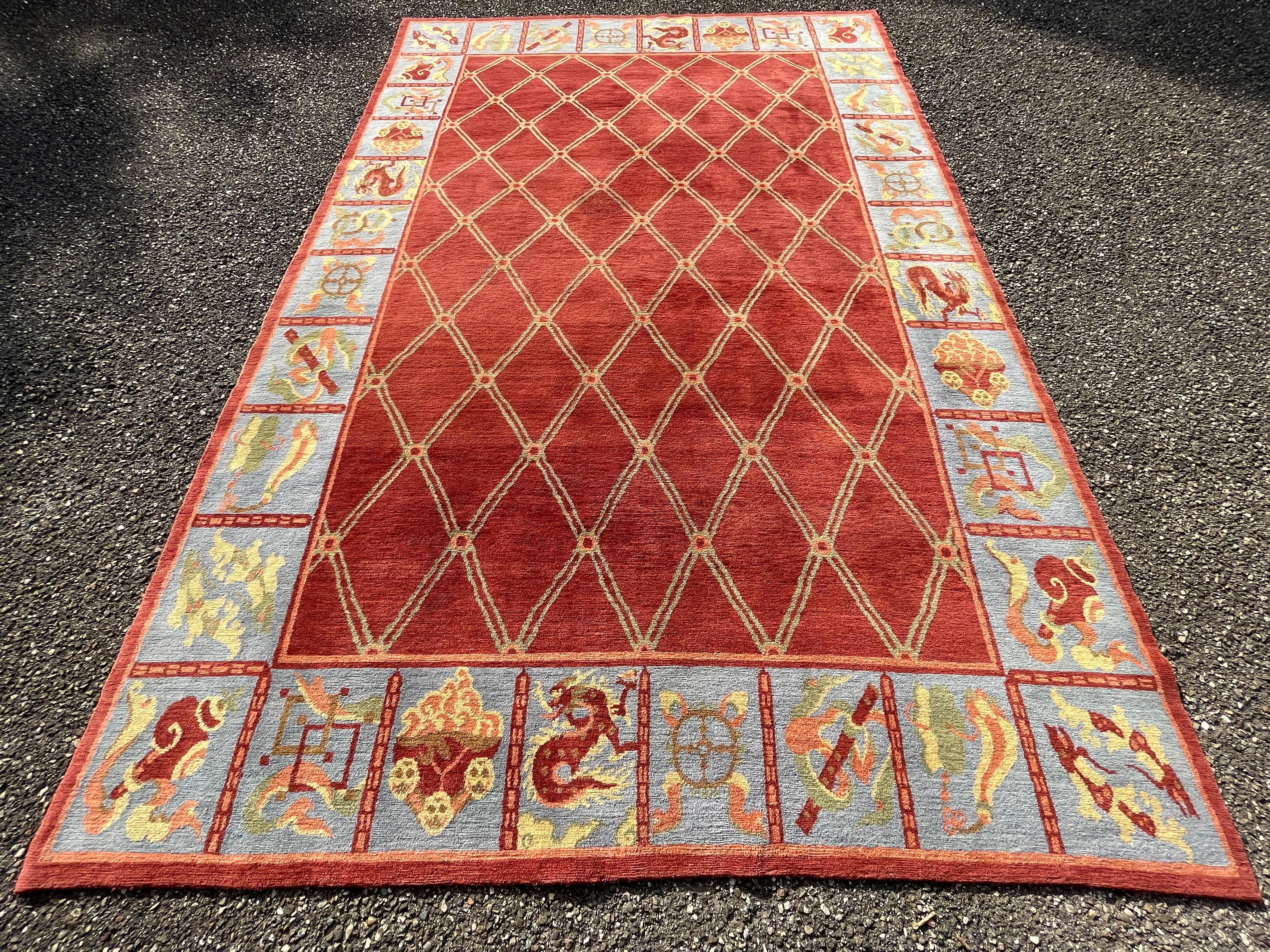 Elegant rug from Tibet, circa 1970.

Woolen rug with checkered decoration on a brick red background framed by a compartmentalized border decorated with stylized symbols and dragons.

Modern Tibetan rugs have been handcrafted for centuries.