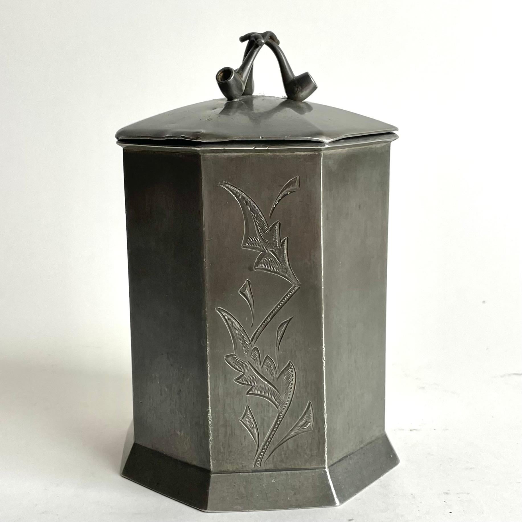 Elegant tobacco jar in pewter with handles in the shape of pipes. Swedish Grace from the late 1920s. Manufactured by A M Berglund in Linköping, Sweden.

Wear consistent with age and use 