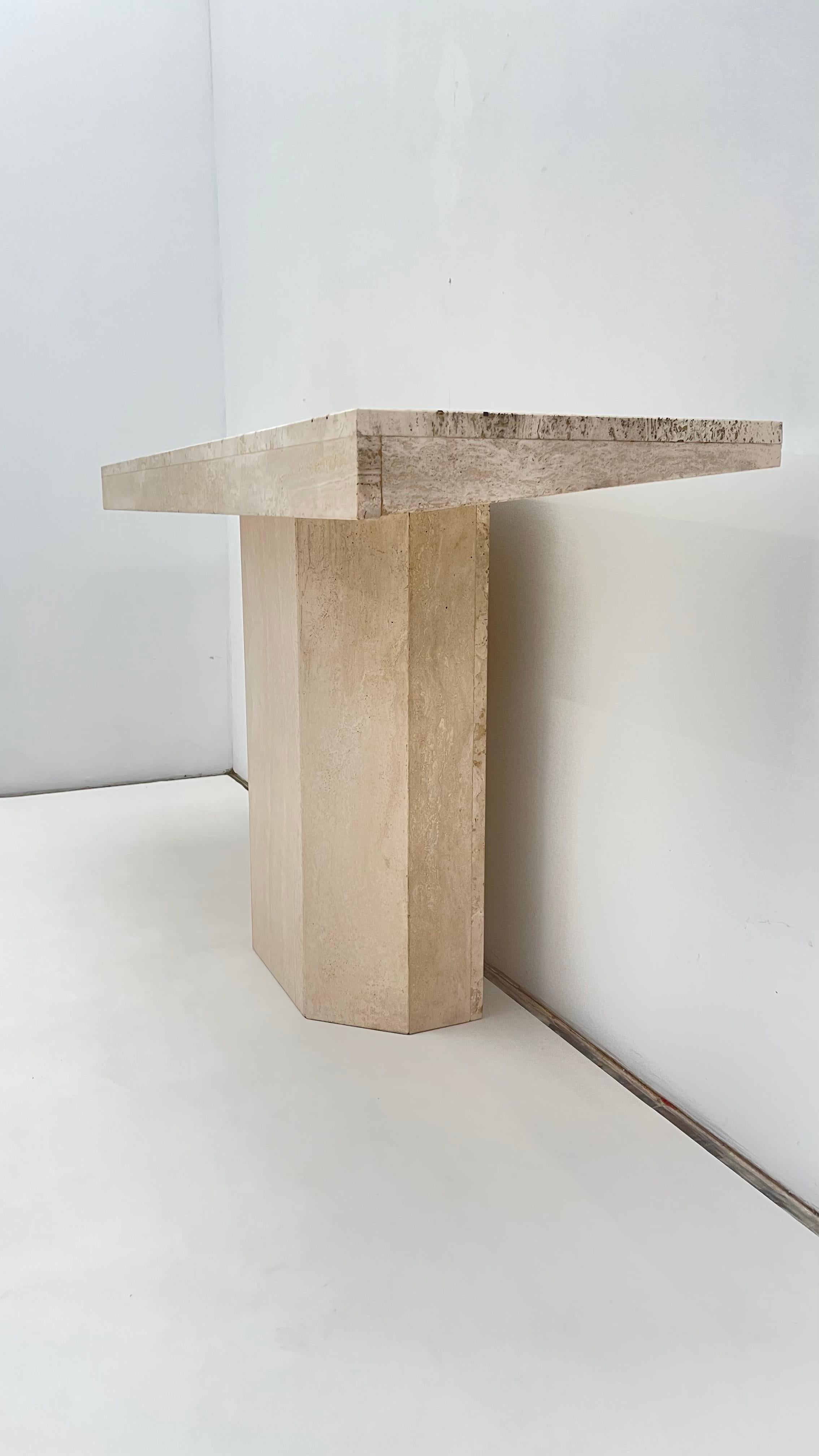 Timeless Travertine Console Table

Handcrafted from natural travertine, the table features a sleek rectangular top that highlights the stone's organic veining and soft beige tones with straight thin inlays lines of brass. The sturdy pedestal base is