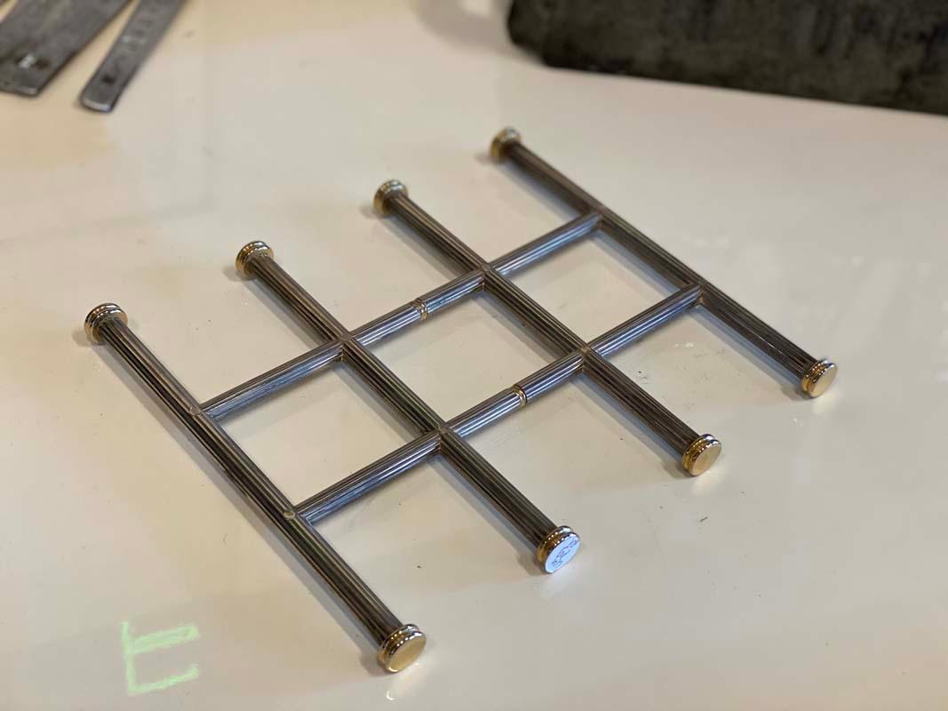 Elegant trivet in Hollywood Regency style. The trivet in classic design comes from France, consists of 6 interconnected bars of chrome-plated metal, partially brass-plated. A beautiful and useful table accessory for the next dinner party!