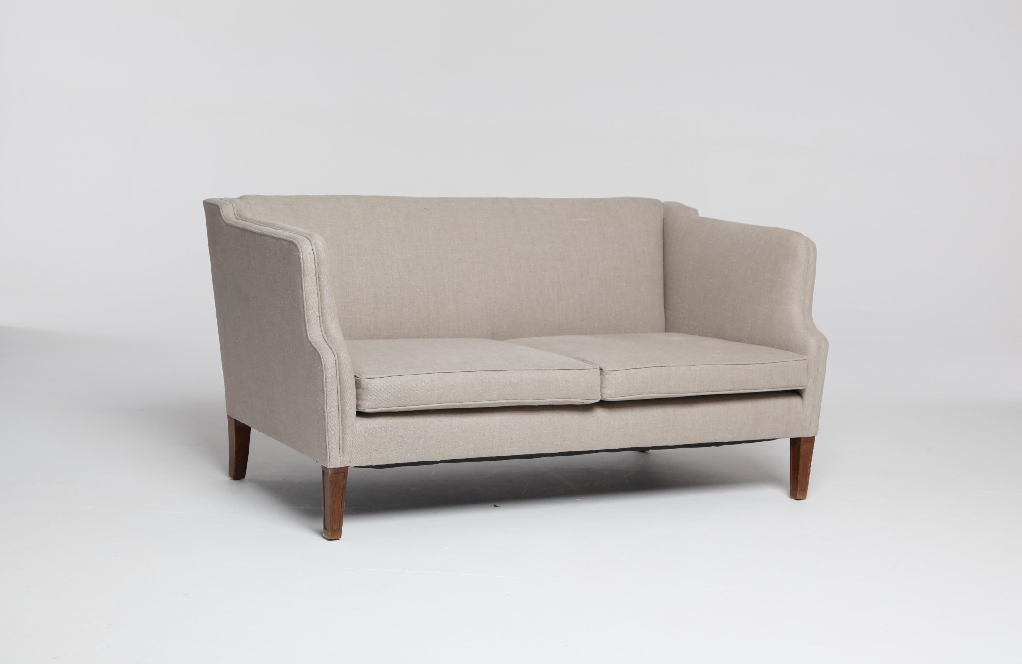 An elegant and Classic Danish midcentury 2-seat sofa or loveseat newly upholstered in natural linen.

Measures: Height at back (highest point) 73.5cm
Depth 77cm
Width 145cm.
 