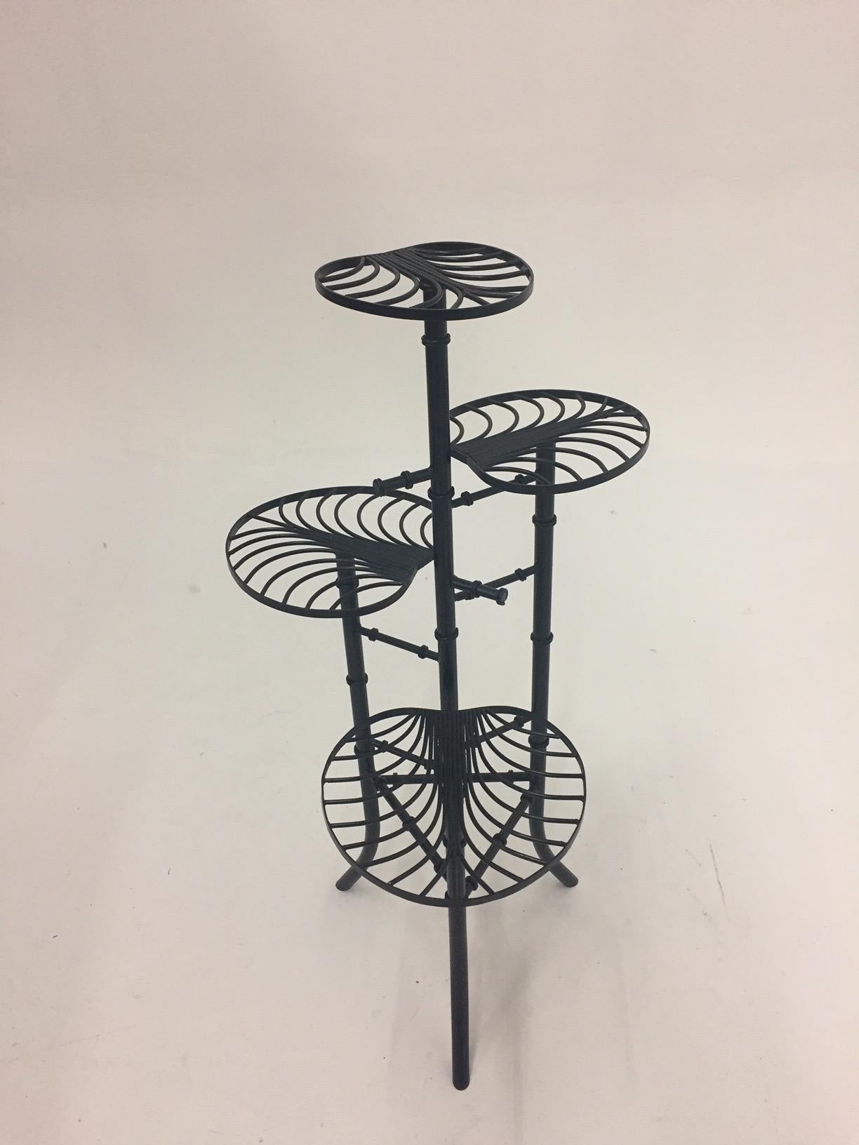A sculptural wrought iron plant stand having 4 levels of palm leaf shaped shelves and shapely faux bamboo legs, very tropical!
Measures: Top leaf 39 H
2nd leaf 31 H
3rd 26 H
lower 19 H.