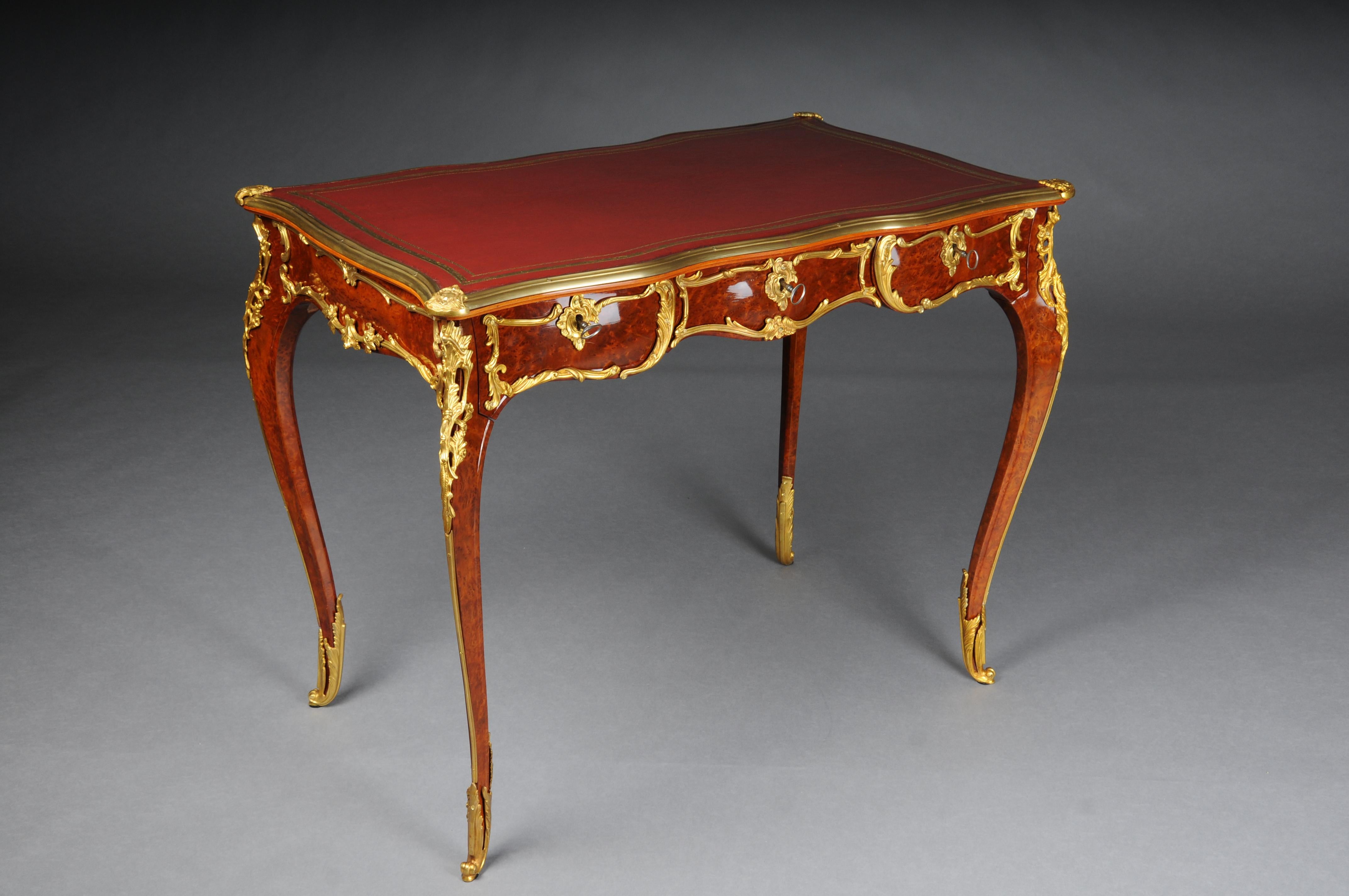 Elegant veneered bureau plat / desk in Louis XV style

Solid beech wood and veneer. Very fine, floral bronze fittings.
Curved and pronounced / arched wooden body. Frame base with four-sided curvature.
3 drawers and wide knee compartment ending on