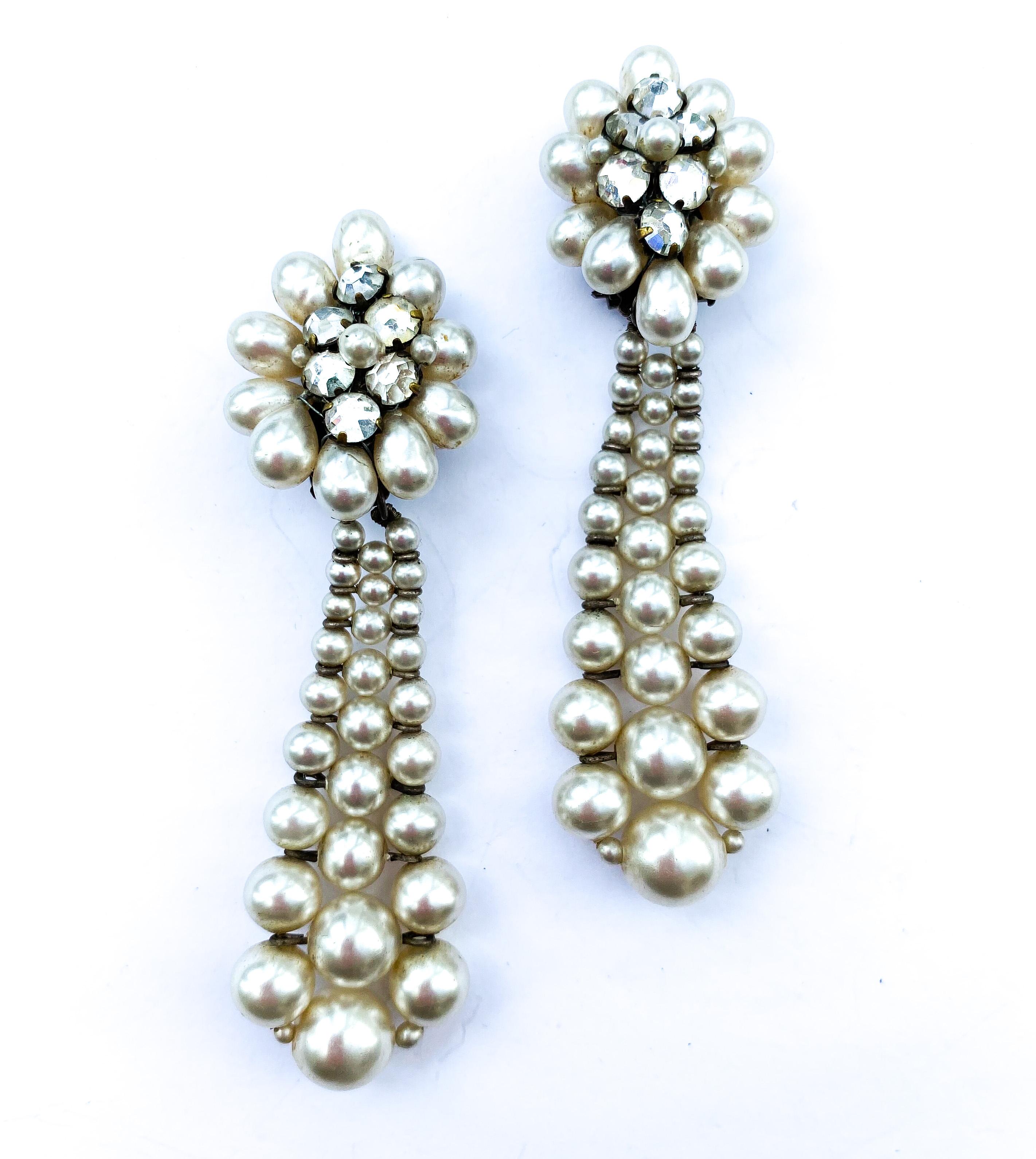 A very long and super stylish pair of faux pearl earrings by Louis Rousselet. Formed of a cluster of oblong pearls fanning out on the ear, a tapered 'knitted' or 'constructed' drop falls away from the cluster. They are set in a silvered wire, the