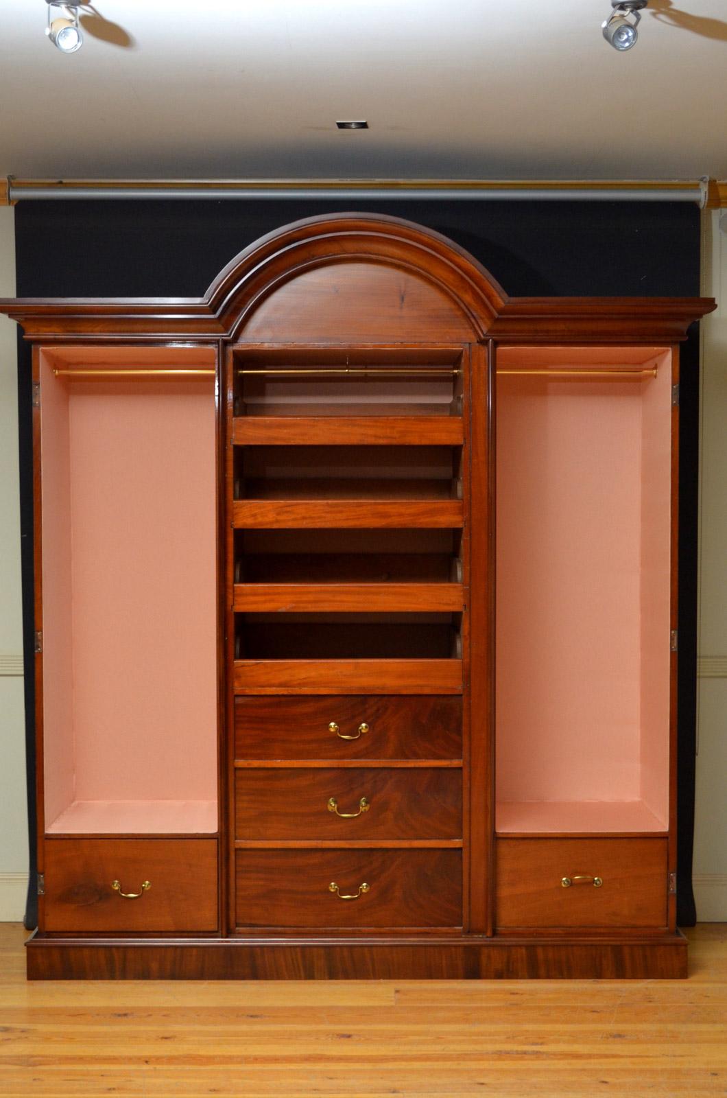 Sn4378, fine quality and very elegant, Victorian three-door breakfronted wardrobe in mahogany, having moulded cornice above figured mahogany frieze and mirrored and arched centre door enclosing original sliders (or short hanging) and drawers flanked