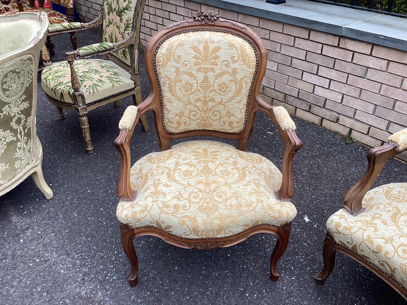Elegant 3 piece salon set ensemble having 2 armchairs and a lovely settee. The frames are made of walnut and feature delicate carvings on the upper crest at the bottom of the frame. The flowers resemble daisies, which is unusual. The upholstery is