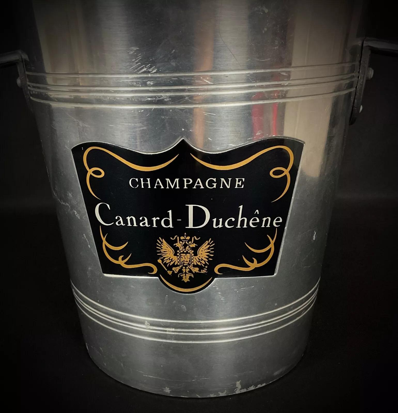 Ajoutez une touche de sophistication à vos réunions avec ce seau à glace à champagne Canard-Duchêne vintage. Fabriqué en aluminium poli, il présente un design minimaliste qui s'intègre à tous les styles de décoration et est idéal pour servir le
