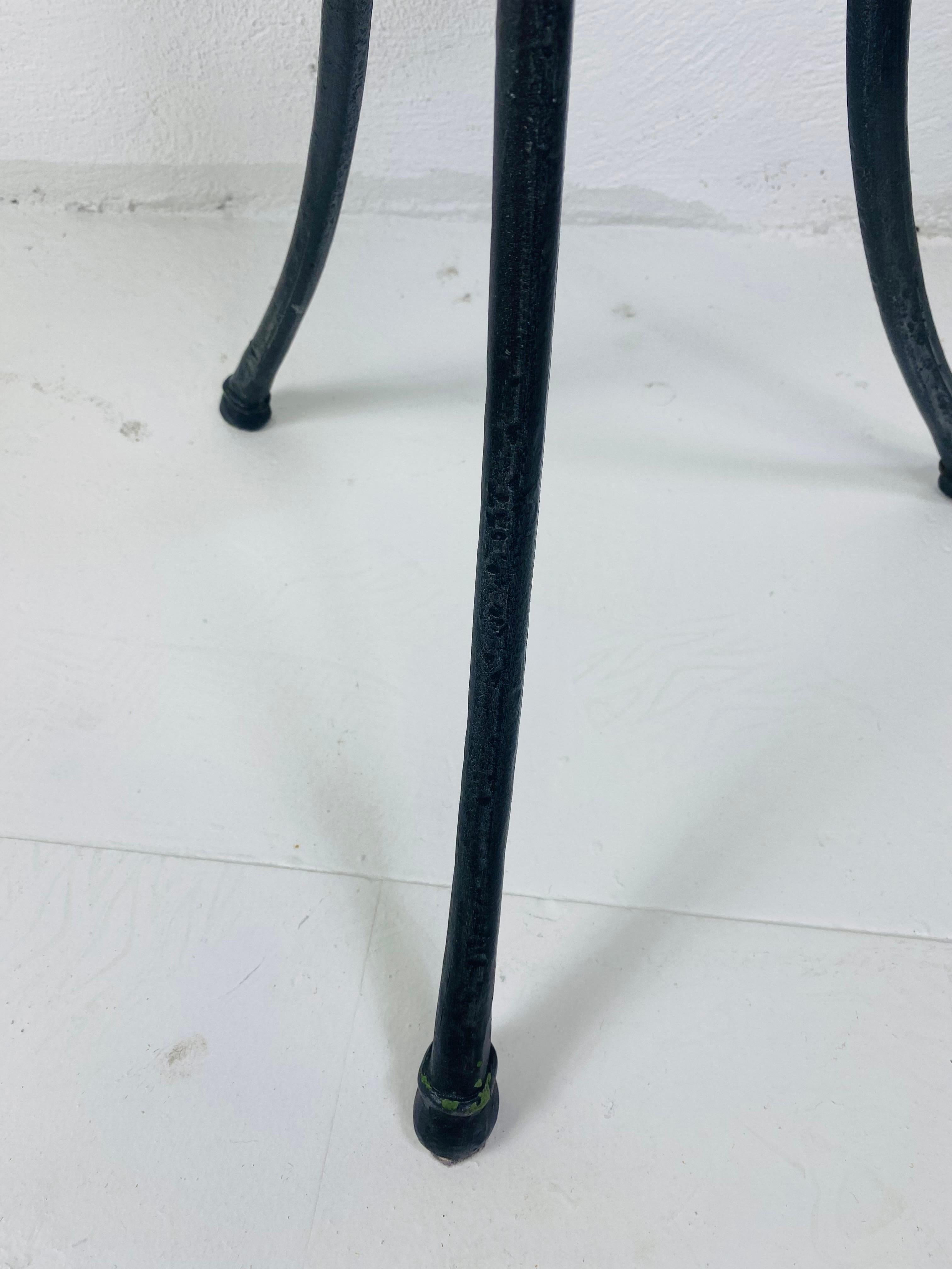 This is an elegant empire inspired marble topped side table by Maitland Smith. This Empire inspired table has a hand forged wrought iron base with three decorative brass wings. This table has a tessellated tan and cream colored marble top. This