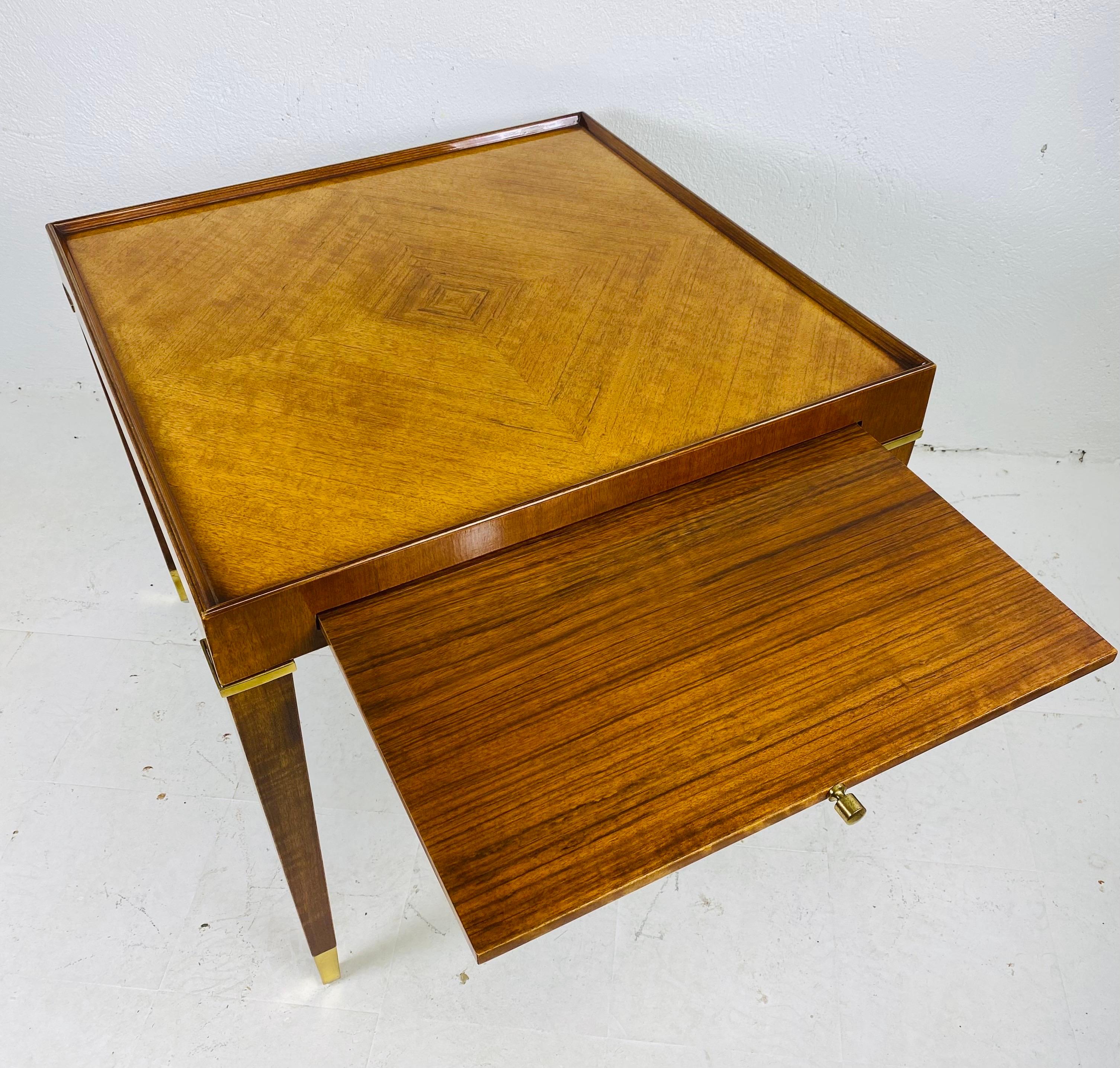 Se trata de una elegante mesa auxiliar vintage de Henredon. Esta mesa auxiliar de nogal tiene una incrustación de rombos en la parte superior con un ligero borde de galera. Esta mesa presenta detalles de latón en la parte superior e inferior de las