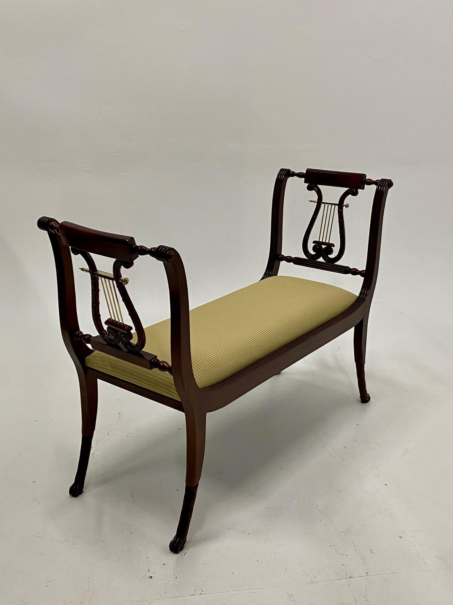 Elegant vintage mahogany and upholstered neoclassical style bench having a marvelous lyre motife, brass accents, and beautiful legs that terminate in animal feet.