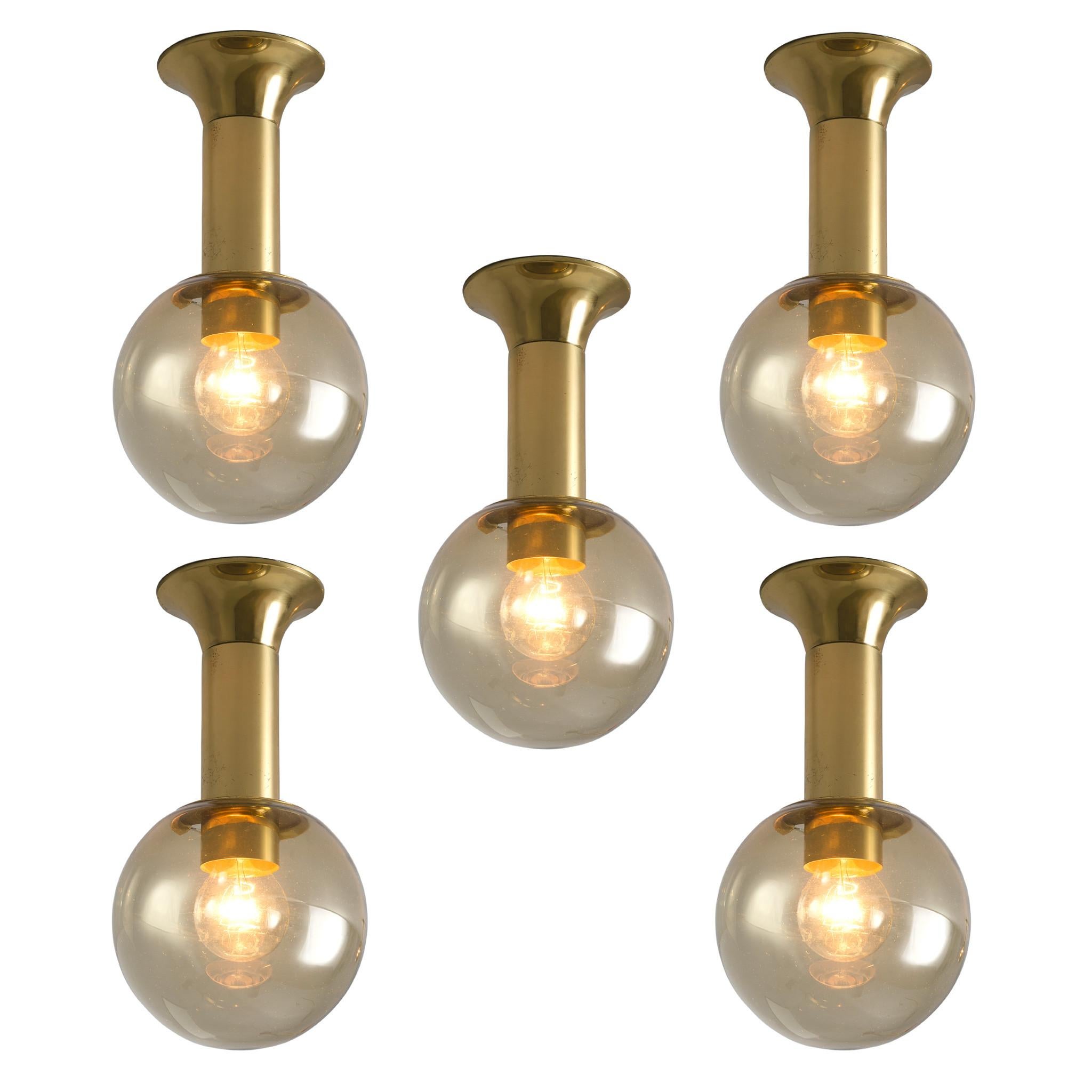 Flush mount lights, in glass and brass, Europe, 1970s.

Set of modern and minimalistic ceiling lights in brass and glass. Each light consist of an elegant, round brass fixture and a glass sphere. Inside the sphere are two light-points. The