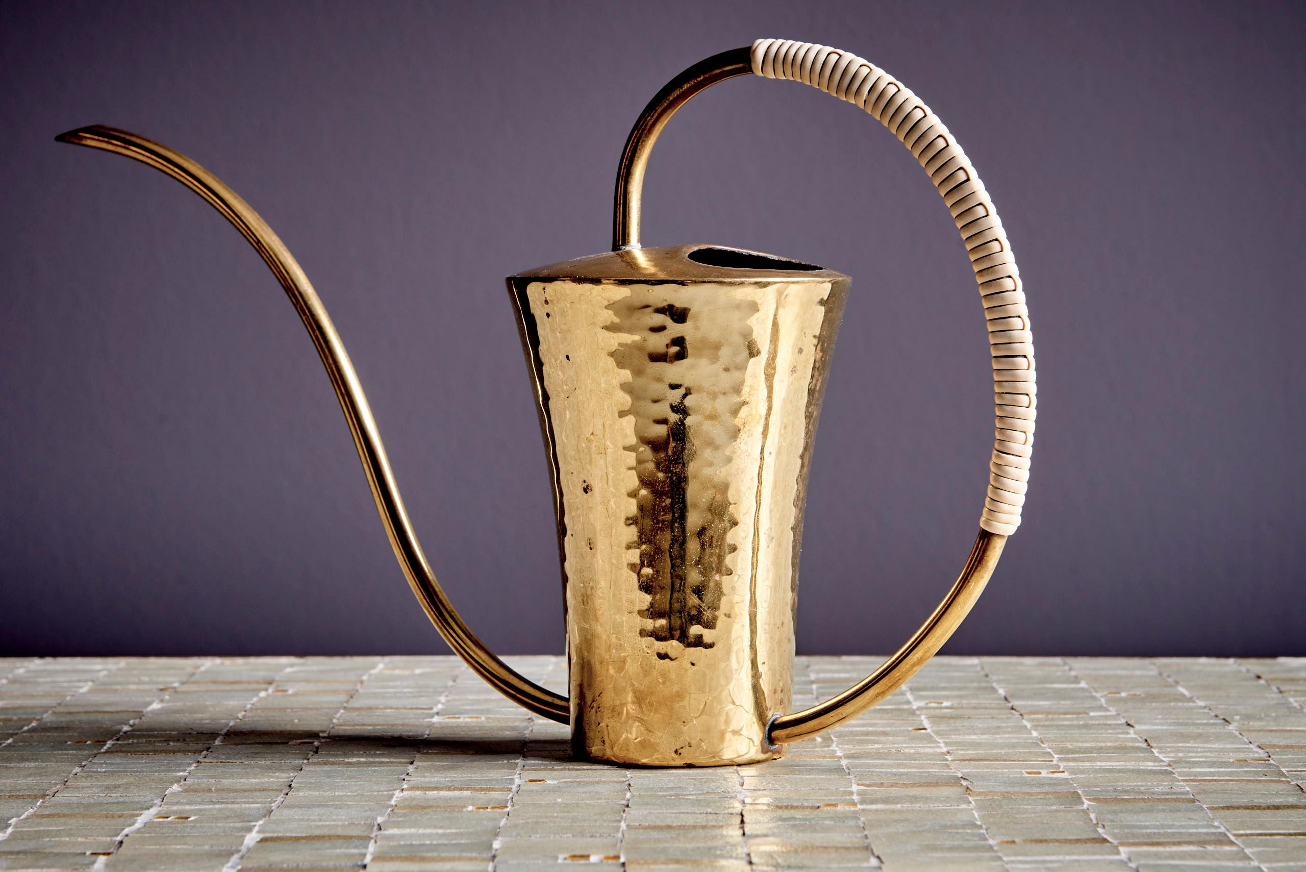 This elegant watering can from the 1960s is crafted from hammered brass, showcasing a beautifully textured surface. Its gracefully curved spout and wrapped handle add both functionality and charm, making it a striking piece of mid-century design.