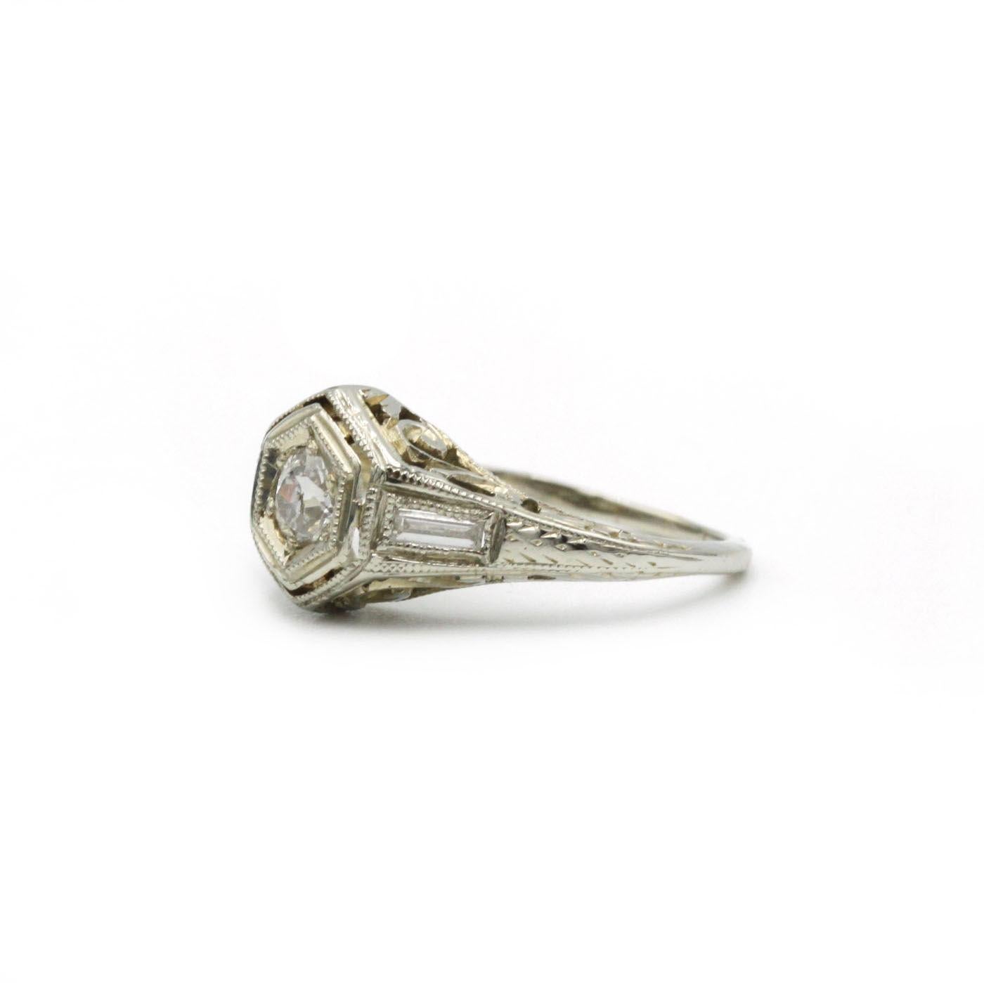 This elegant ring, crafted in 18 K white gold (750‰), features a sparkling round brilliant-cut diamond of approximately 0.30 ct as its centerpiece. Flanking the central stone on either side are two tapered baguette diamonds, which accentuate the
