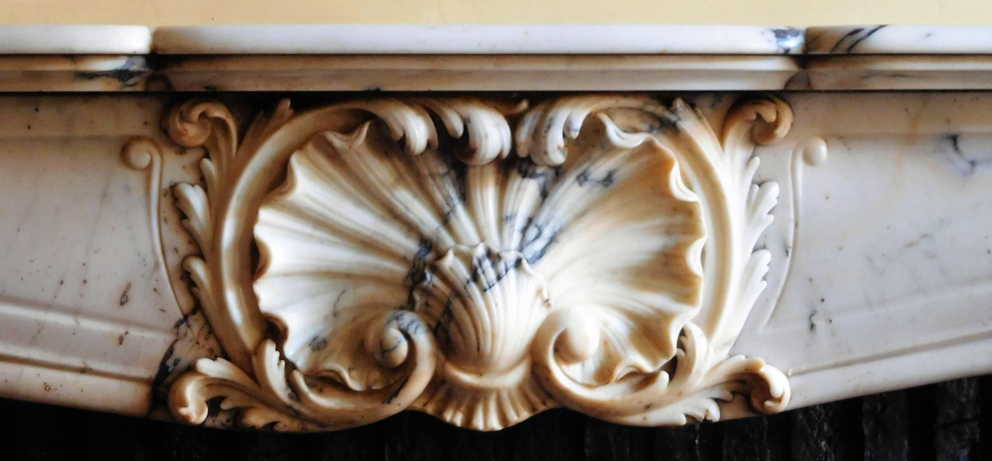 This elegant, antique Louis XV style fireplace in Rococo-manner was made in the mid-19th century.
It's made in a very delicate and highly-valued marble: Paonazzo
This fireplace is characterized by sinuous lines. Large windings carved in the marble