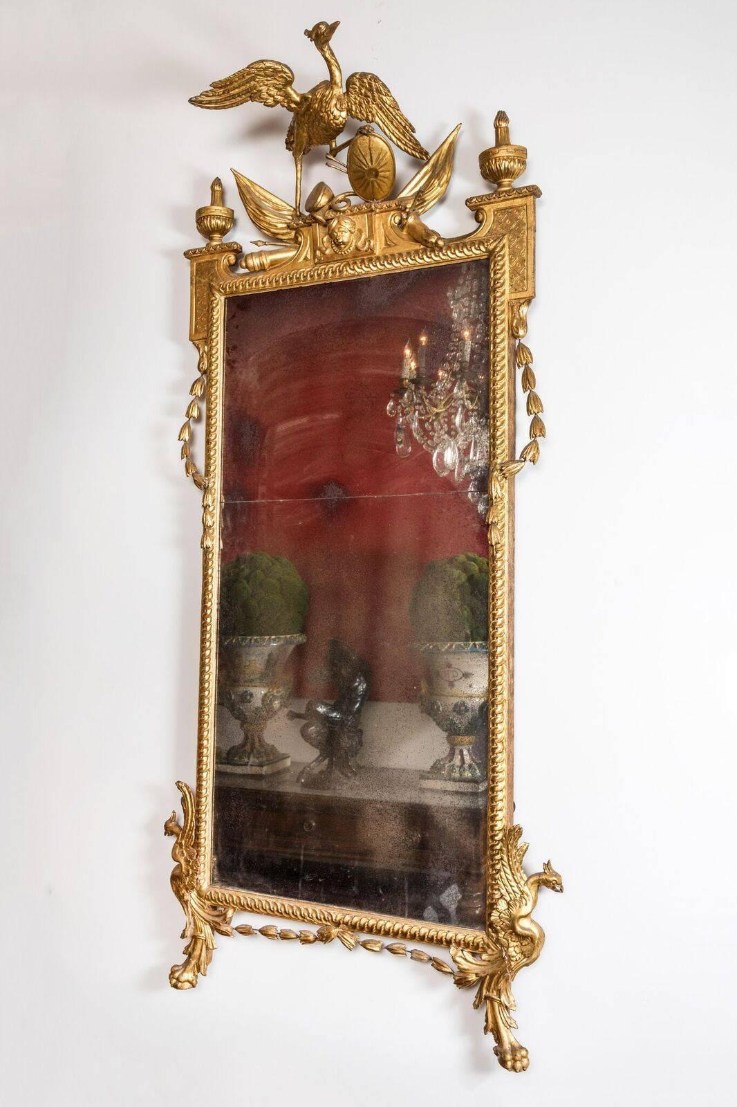 Beautifully hand-carved, gessoed, and 22-karat gold gilded frame featuring lower corner bird-reliefs above claw feet, and cascading, foliate swags throughout. The whole crowned by a grouping featuring a central, winged phoenix clutching a shield,