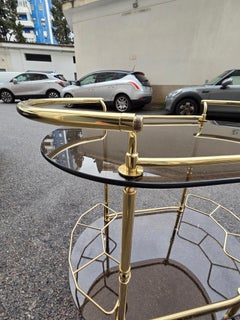 Elegante carrllo de bar ovalado en latón macizo y cristal ahumado años 70 Italia