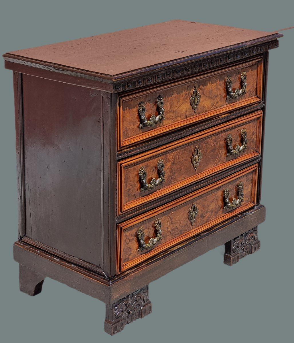 Elegante canterano veneziano a tre cassetti, realizzato nel XVIII secolo. Il mobile presenta una struttura solida in legno massiccio, con fianchi e piano superiore in legno ebanizzato, mentre i frontali dei cassetti sono lastronati in una pregiata