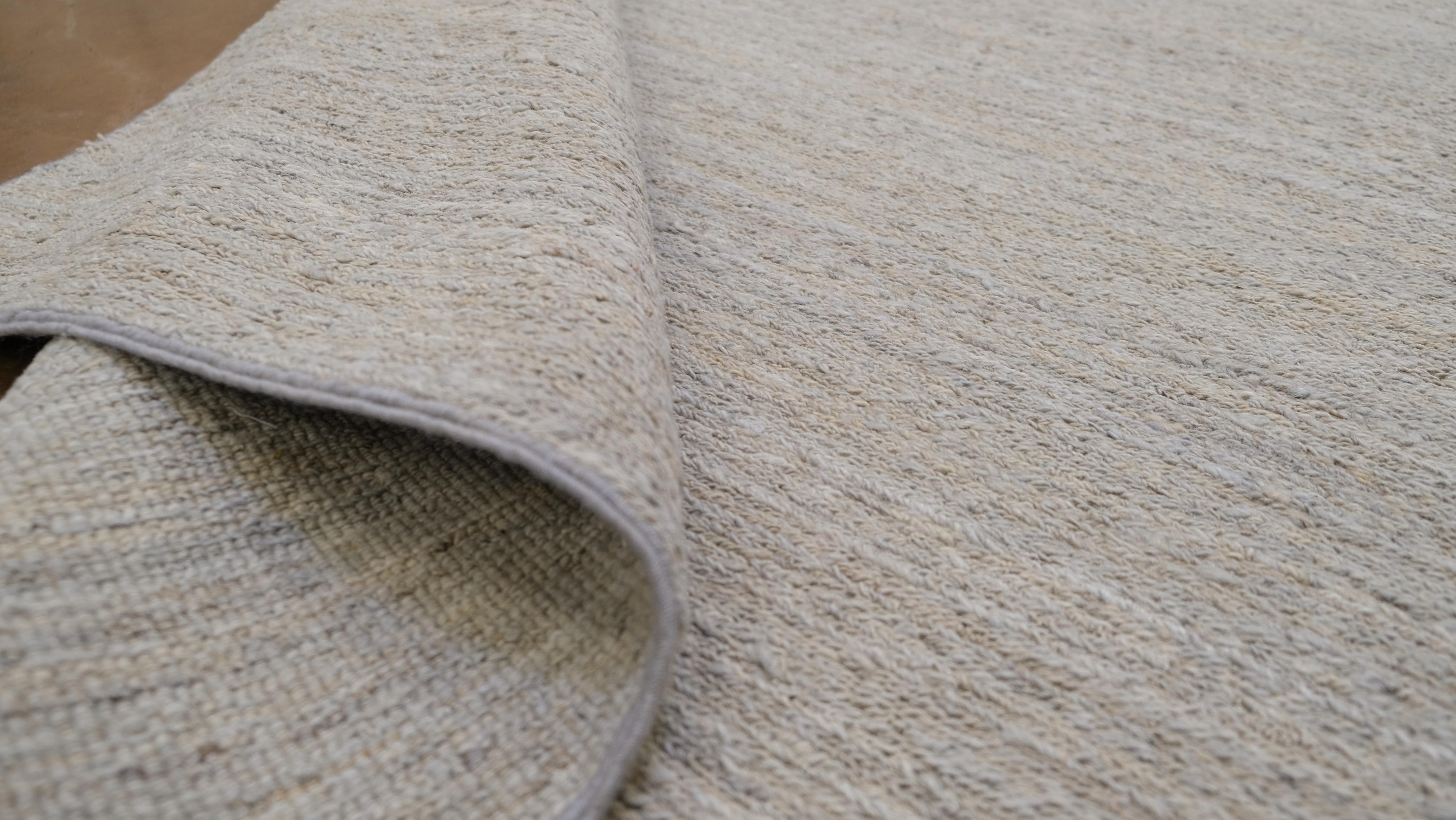 Verschönern Sie Ihren Wohnbereich mit diesem eleganten, schlichten handgeknüpften Wollteppich aus Pakistan. Mit seinem minimalistischen Design in weichen, neutralen Beigetönen bietet dieser Teppich eine unaufdringliche Raffinesse, die perfekt ist,