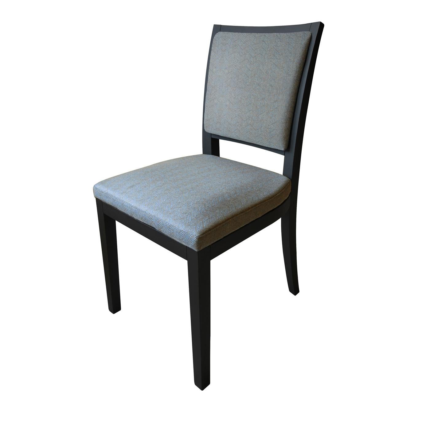 This chair is marked by a surprisingly simple silhouette that exalts its classic sophistication. A sturdy yet comfortable piece, it is composed of a stained solid ash frame with robust legs and slightly slanted backrest, upholstered in an elegant