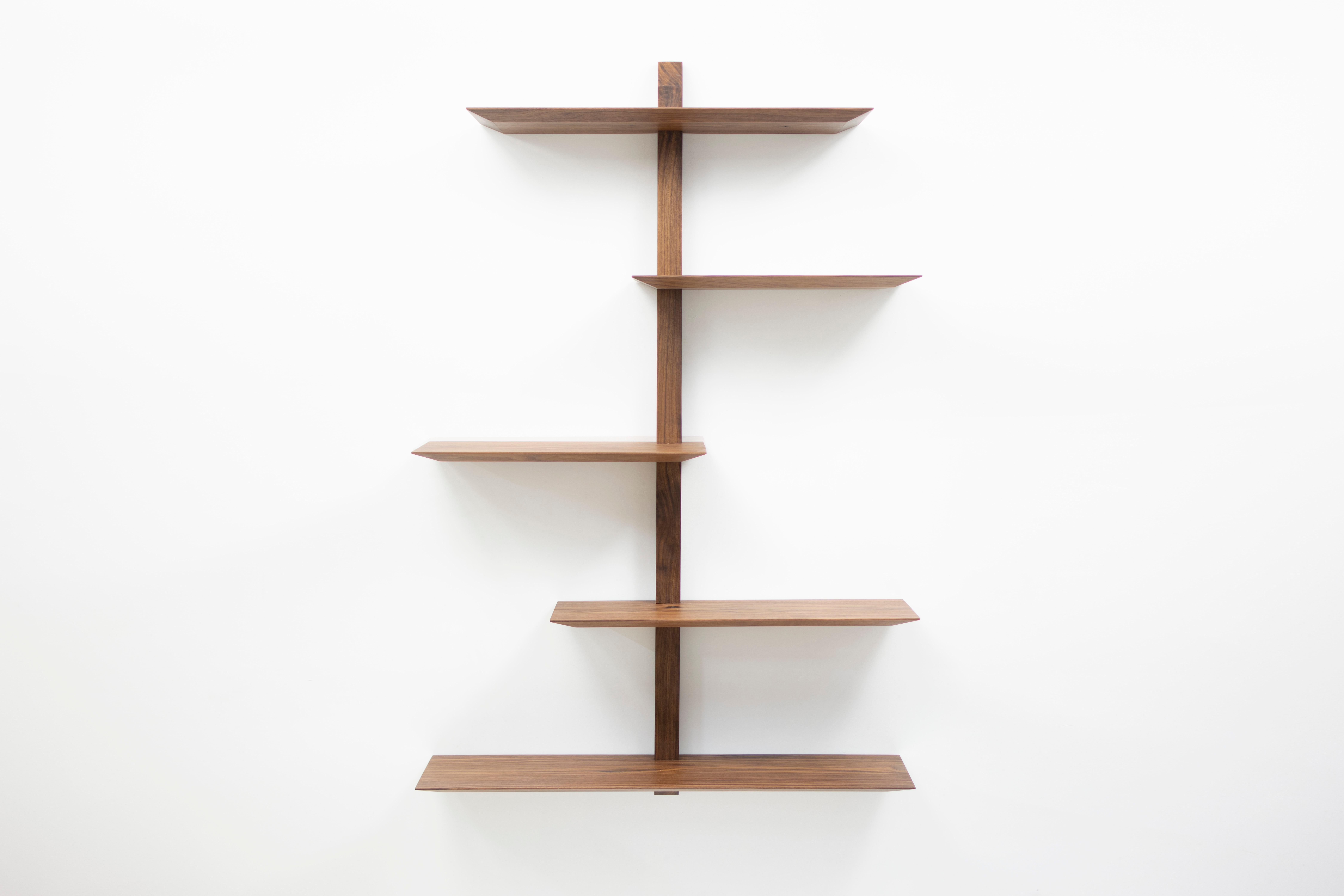 The Elemen shelving system features solid walnut shelving with a gem cut edge, joined with single vertical members to produce a striking and dynamic visual statement. The concealed wall bracket mounting system makes installation quick and painless,