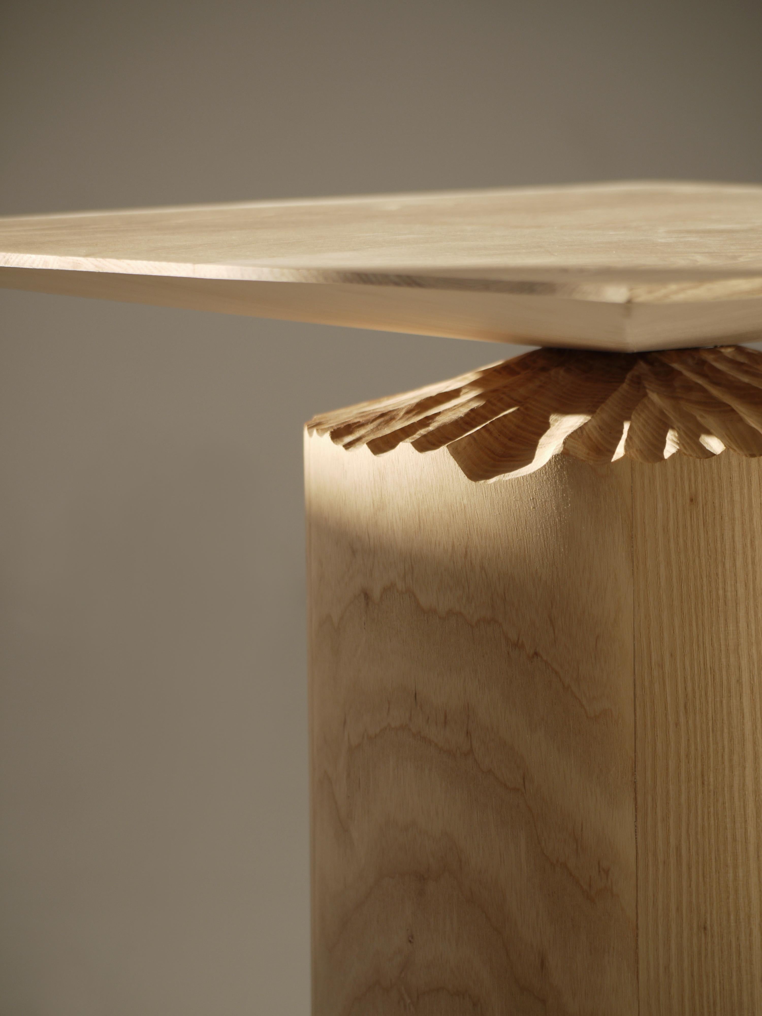Element is a side table in solid ash that plays with angles and perspectives. Discover the carved detail, inspired by the shape and surface left on trees chewed on by beavers. By referring to the tactility of trees and the warmth of wood, the