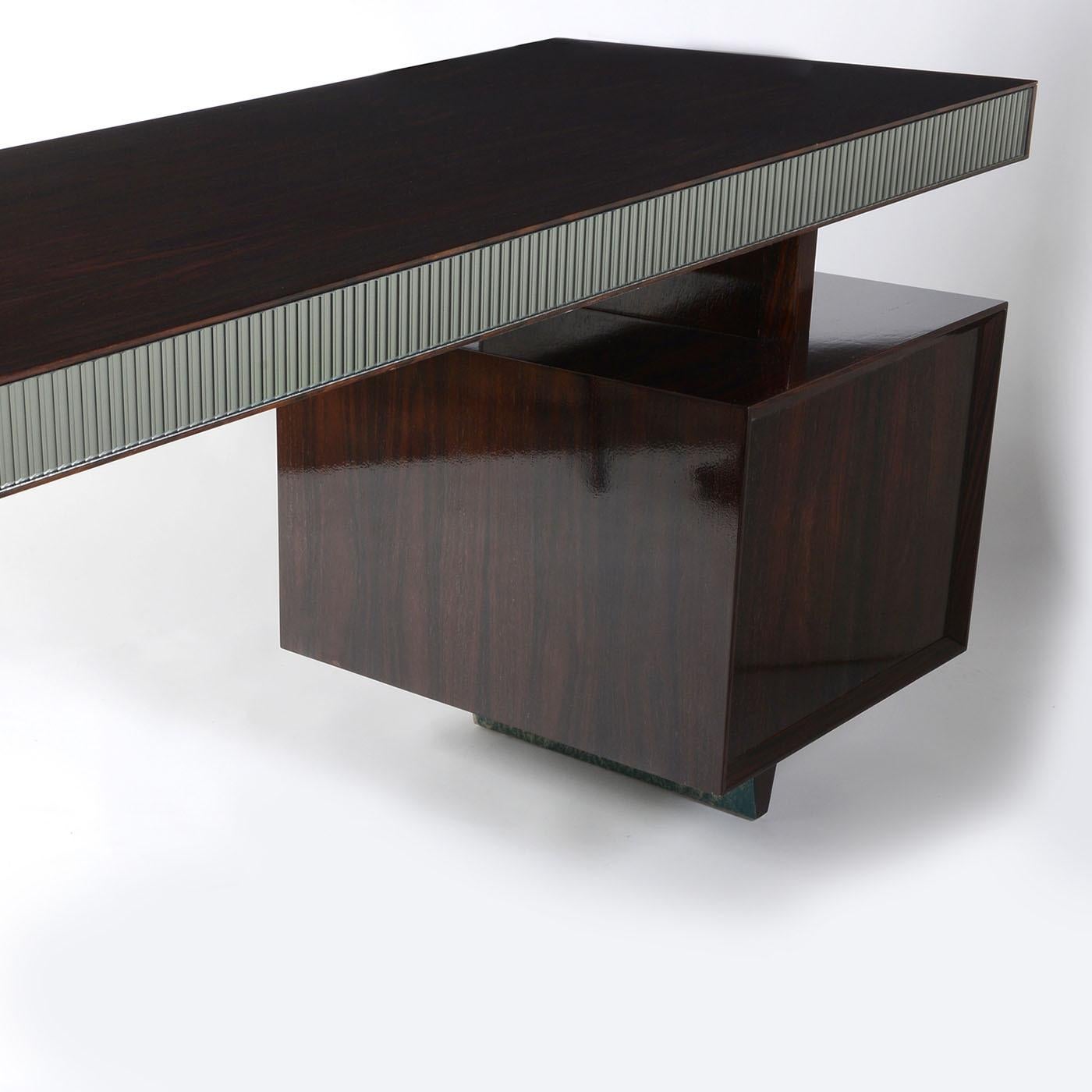 Plush detailing meets a bold and dynamic structure in this superb desk. Offered in a stylish glossy finish, the lovely India rosewood veneer couples with luminous profiles covered in textured smoky mirrored glass that seal its luxurious and