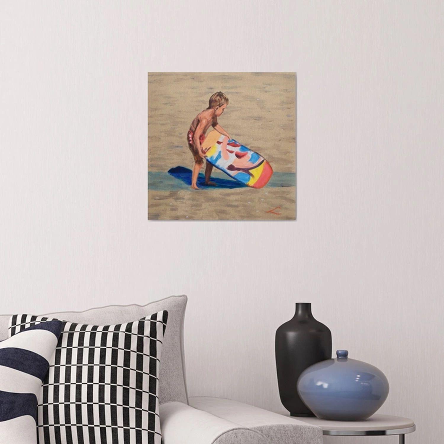 Das Bild zeigt einen sonnigen und luftigen Tag am Strand, an dem ein kleiner Junge mit einem bunten Boogie Board spielt, das im Sand liegt. Der mit einer Badehose bekleidete Junge hat seine linke Hand auf das Boogie Board gelegt. Diese Szene wurde