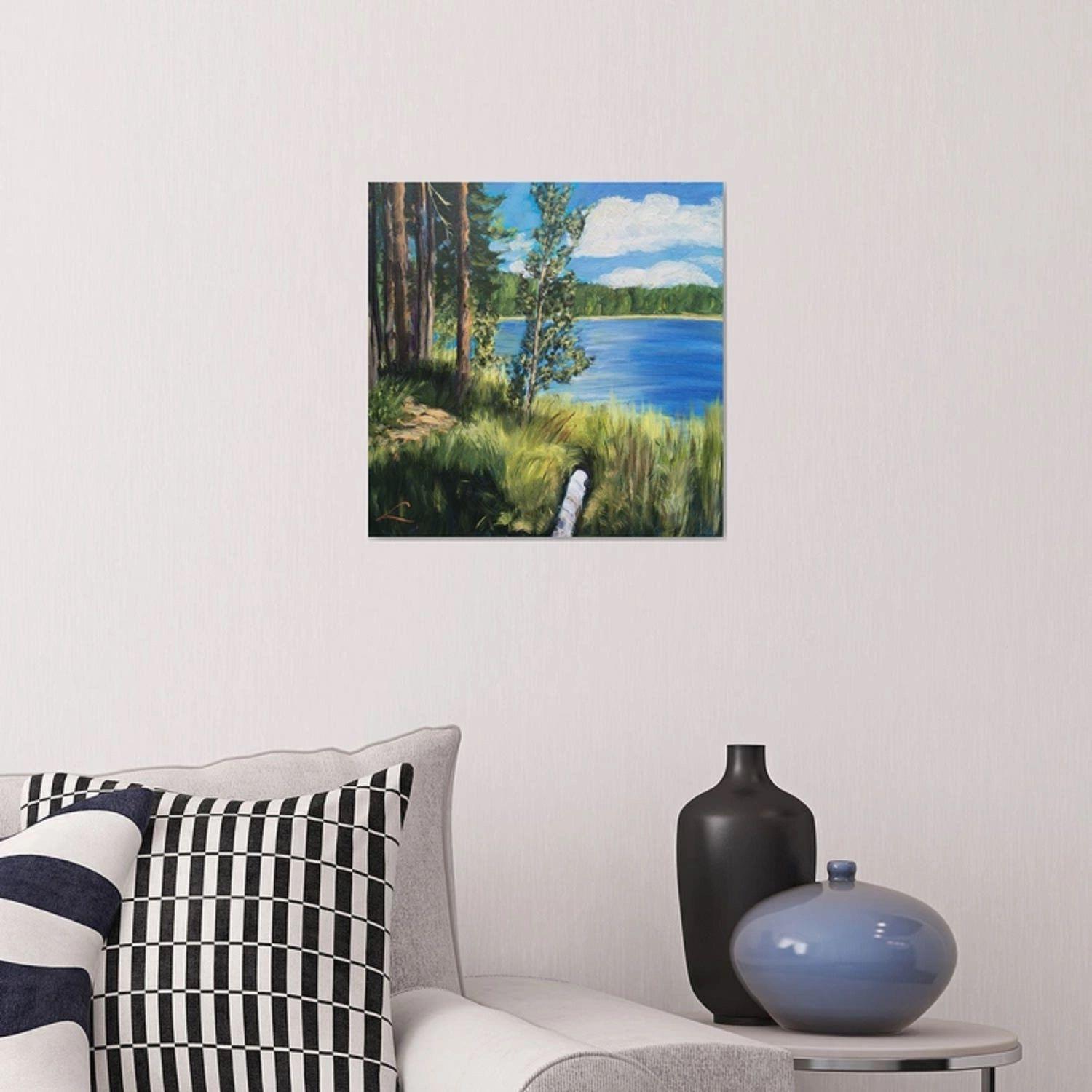 Das Gemälde zeigt einen ruhigen See, der von einer malerischen Landschaft umgeben ist. Auf dem Kunstwerk erstreckt sich ein leuchtend grüner Wald unter einem strahlend blauen Himmel bis zum Horizont. Hoch aufragende Kiefern stehen stolz in der Nähe