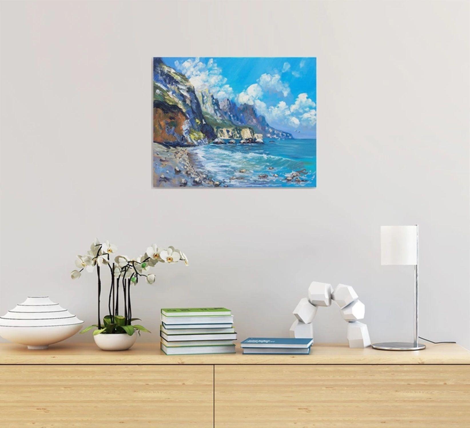 Se trata de una pintura al óleo de una escena costera que representa un paisaje marino vibrante y natural. En primer plano, hay una playa de arena adornada con numerosos guijarros. La playa conduce a una extensión de mar azul, que se encuentra con