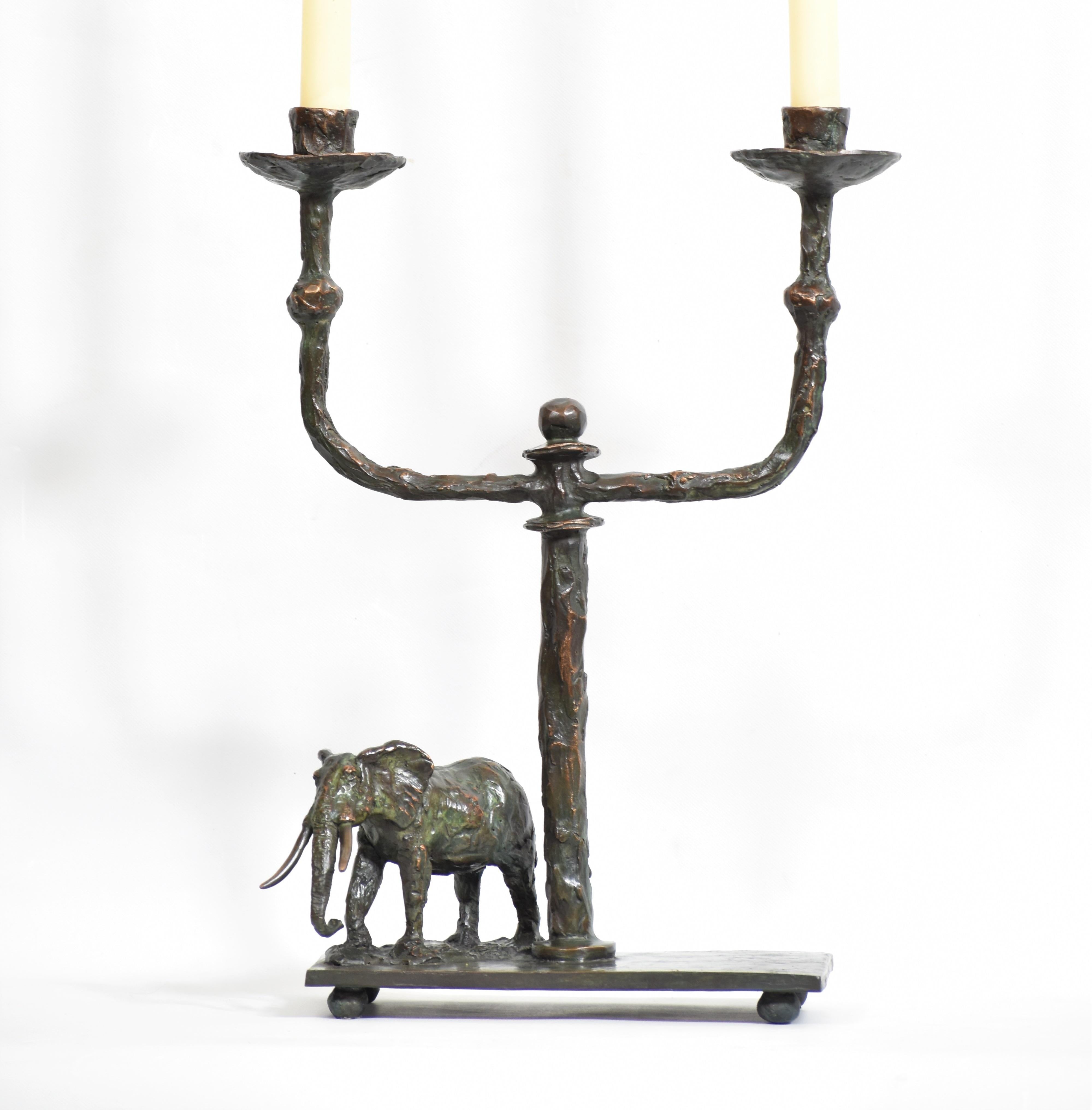 Elefanten-Kerzenleuchter aus Bronzeguss
Dieser Leuchter, der Kunst und Funktionalität verbindet, ist mit einer Bronzeskulptur des Elefantenbullen, dem Wahrzeichen Afrikas, ausgestattet. In Braun schwarz patiniert mit einem Hauch von Verdigris. Jedes