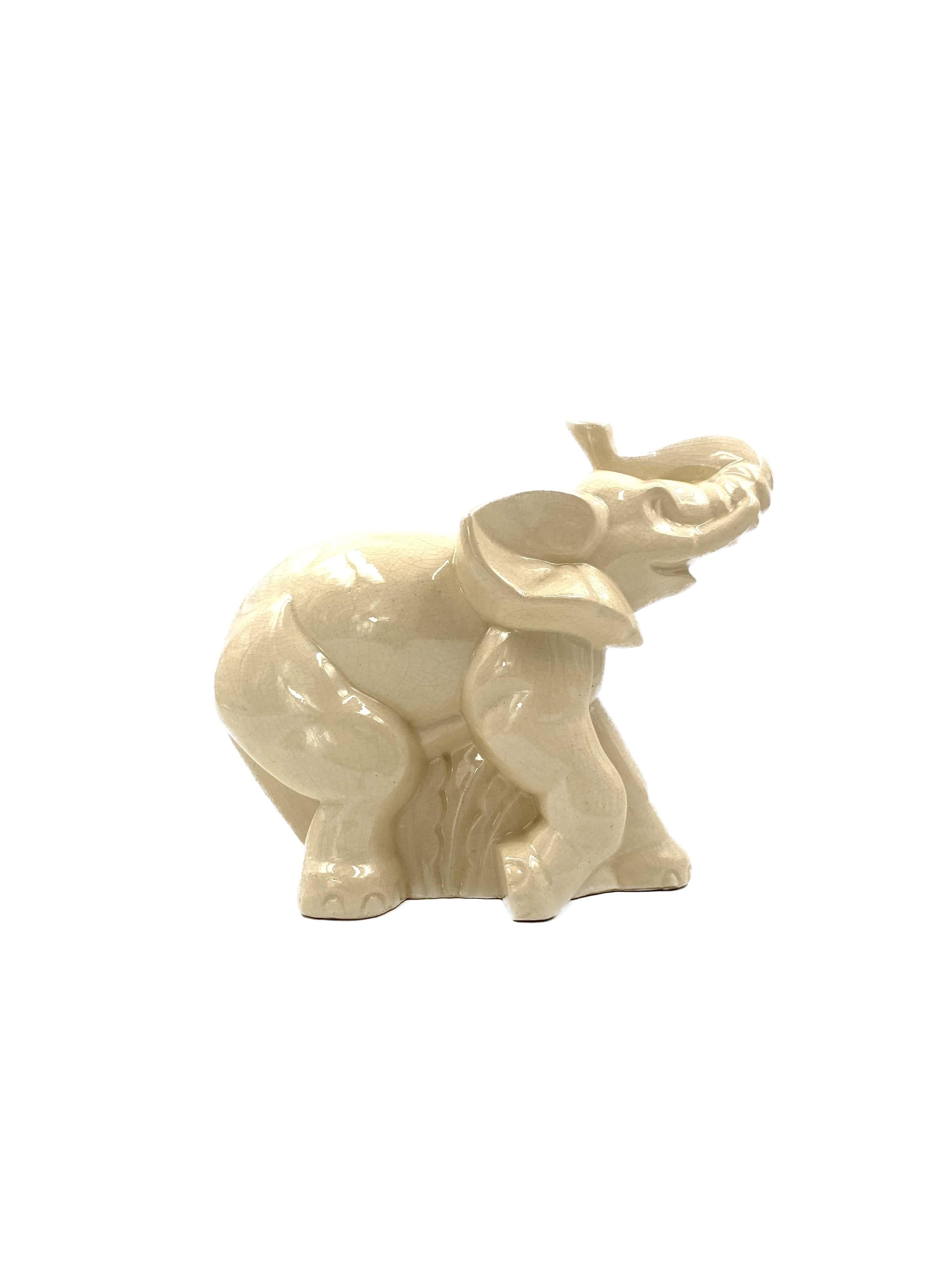 Art Deco elephant sculpture designed by Fontinelle.

Belgium 1940s

cream / ivory craquelé glazed earthenware

Marked on the base with N. 66, there is a mark on the foot, but this can not be read well.

Measures : 29H x 32 x 17