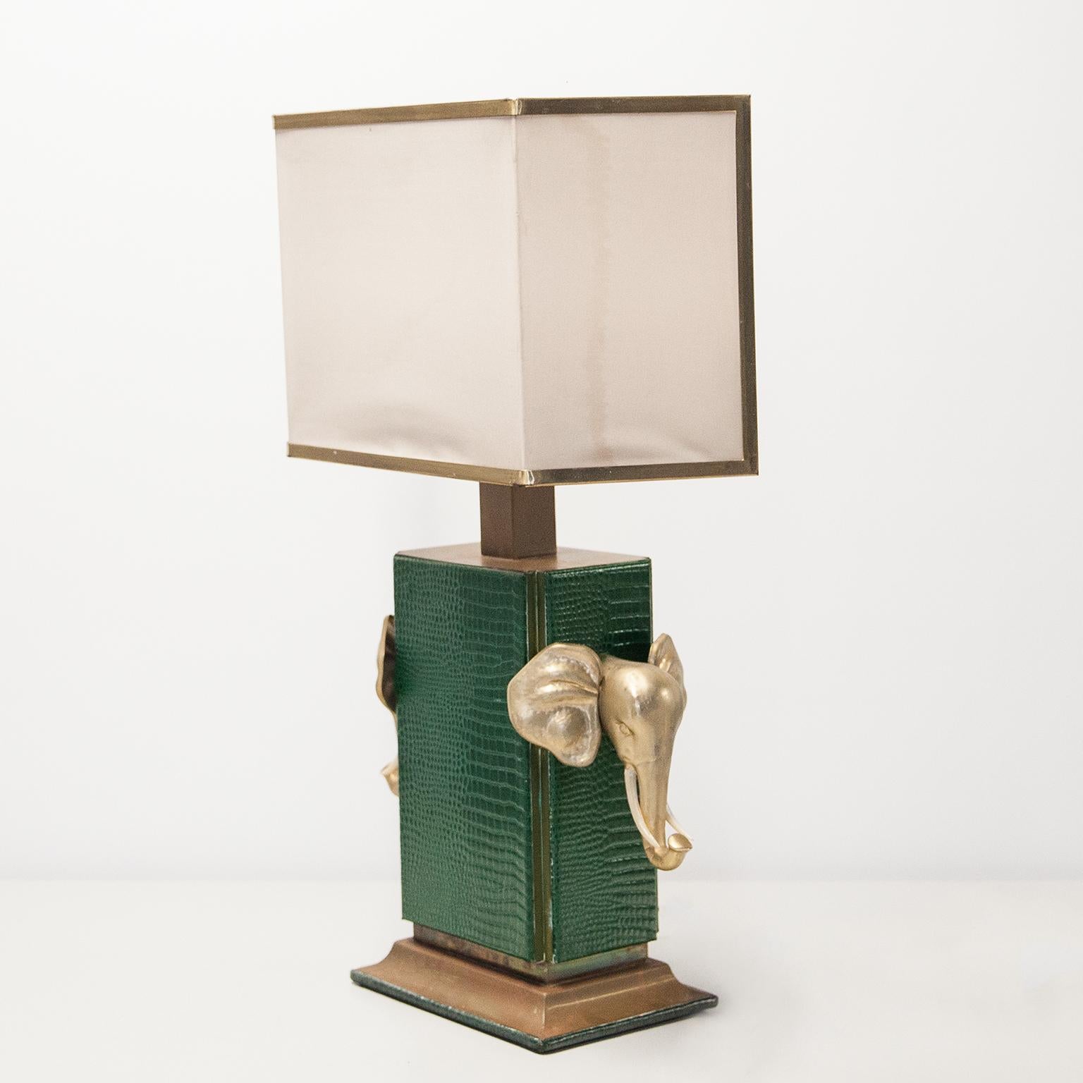 Elegant Table lamp decorated with golden elephant head on a base of green fake crocodile leather and brass with a fabric shade. Made in the style of Maison Jansen in France 1970s.
