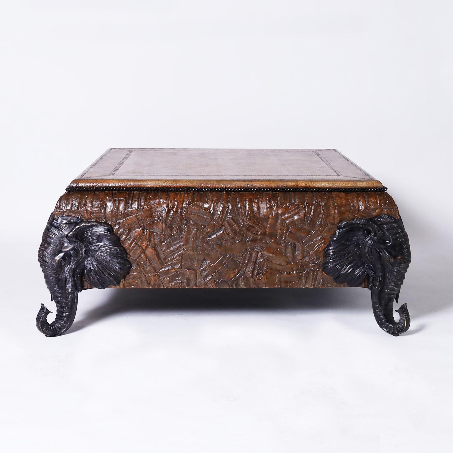 British Colonial style coffee table featuring a variegated tooled leather top over a case with a coconut shell mosaic and bronze elephant head legs. Signed Maitland-Smith on the bottom.