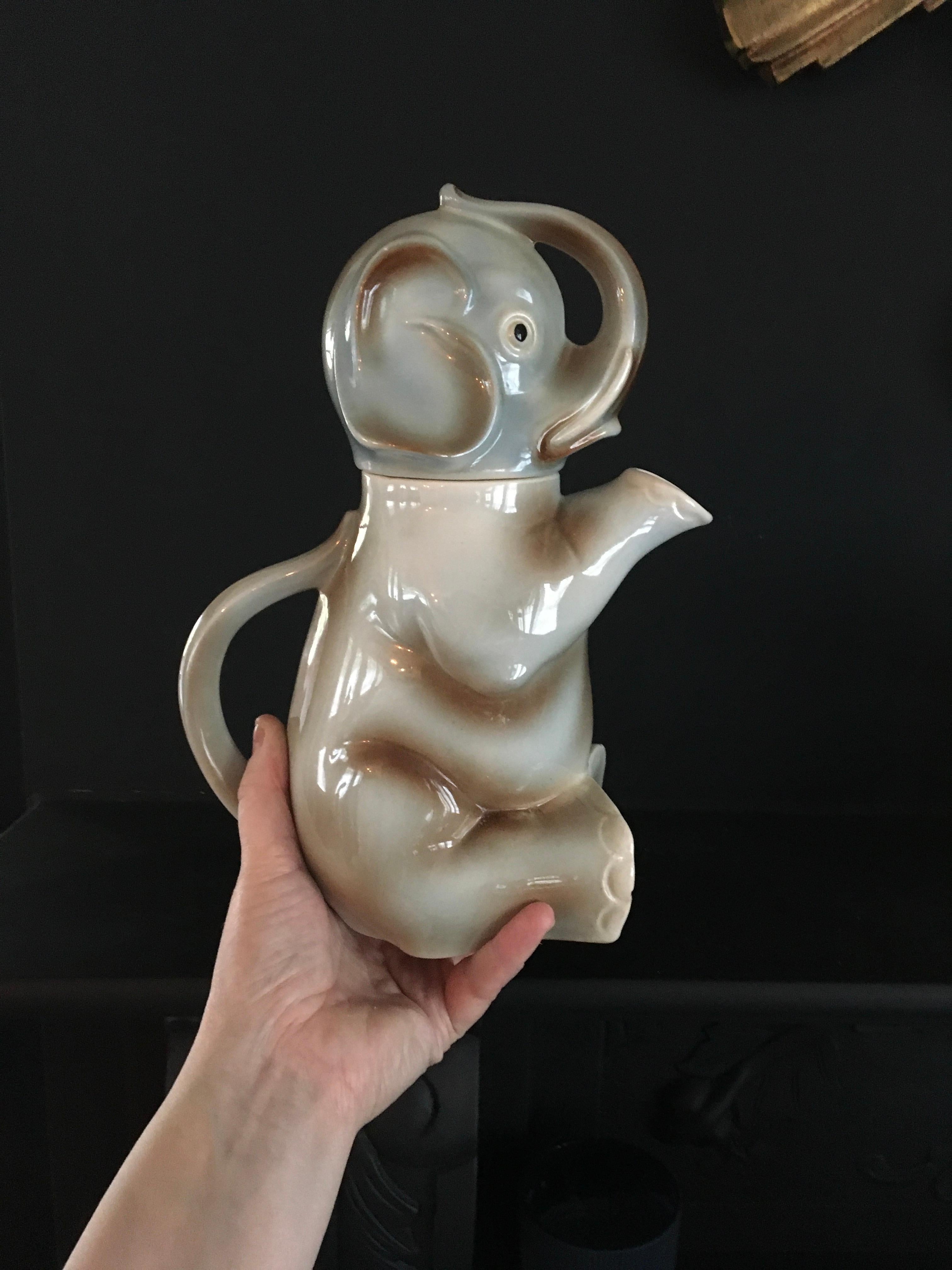 Elephant pitcher - elephant jug. 
A beautiful vintage pitcher in the shape of an elephant. 
It's a seated elephant sculpture with his feet in front and his trunk over his head. 
At the back you find the handle so you can pour the water, soda etc
