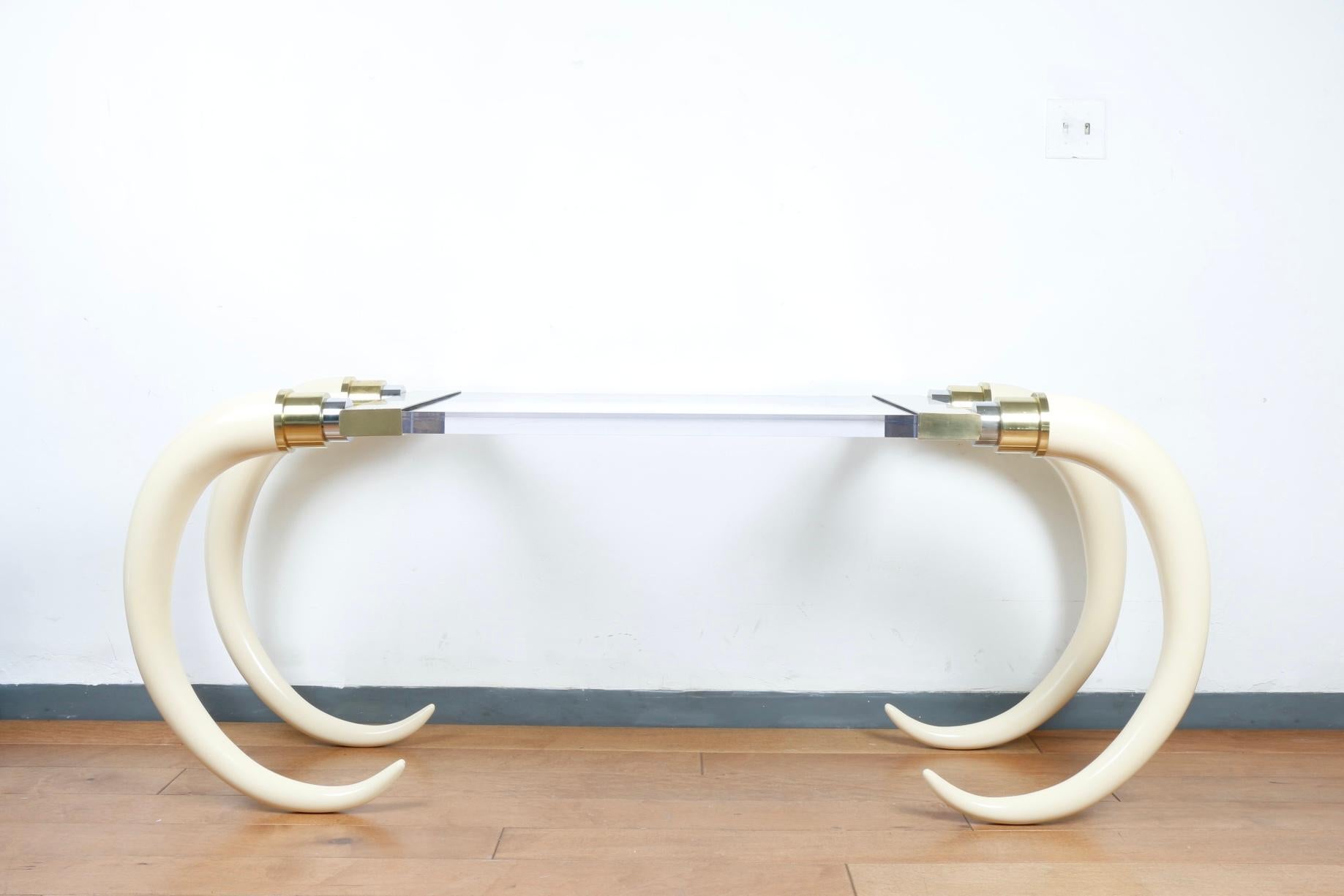 Beautiful faux elephant tusks with brass and chrome accent bases connected to a thick lucite top. Brass and chrome has signs of use. Tusks are sturdy and well kept. Heavy table with nice detail and beautifully designed.