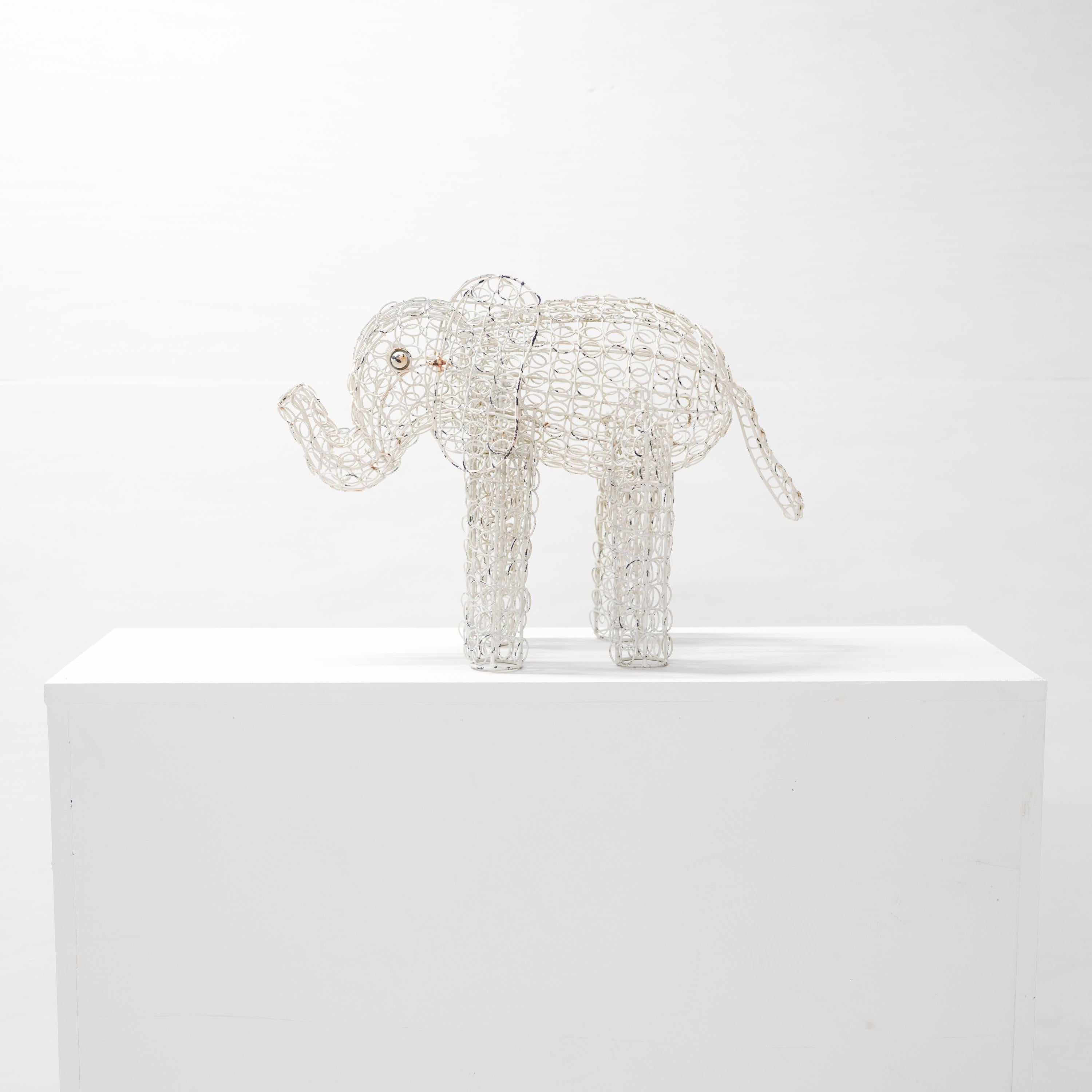 A delightful circa 1940s wire topiary form with original white paint and minor rust staining. Created from loops upon loops, this whimsical elephant is today a gorgeous minimalist sculpture. 

Each eye is unaccountably expressive and the legs,