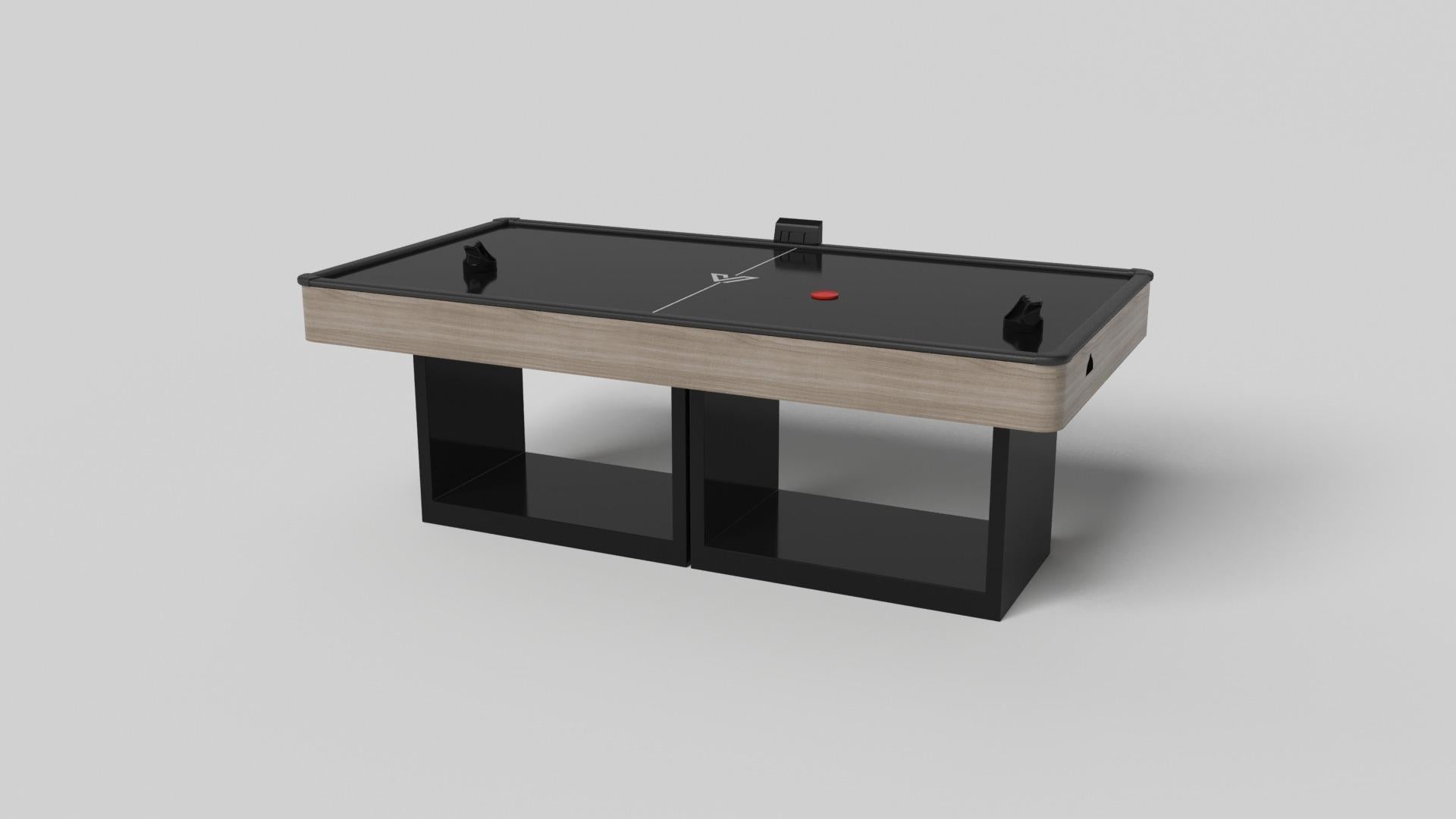 Apoyada en dos pedestales rectangulares abiertos como base, esta mesa de hockey de aire artesanal es moderna y minimalista por su combinación de formas simples y geométricas. Visto de frente, el uso del espacio negativo es evidente; visto de lado,