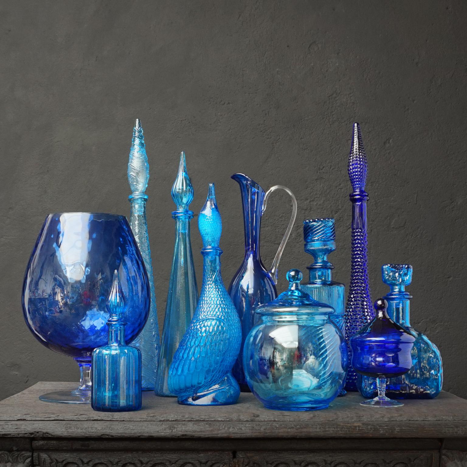 Very decorative blue set of eleven different size Italian blown and pressed glass bottles.
Five genie bottles, a pressed Brutalist decanter and blown clear and blue glass bonbon or candy jars in different shapes and different shades of