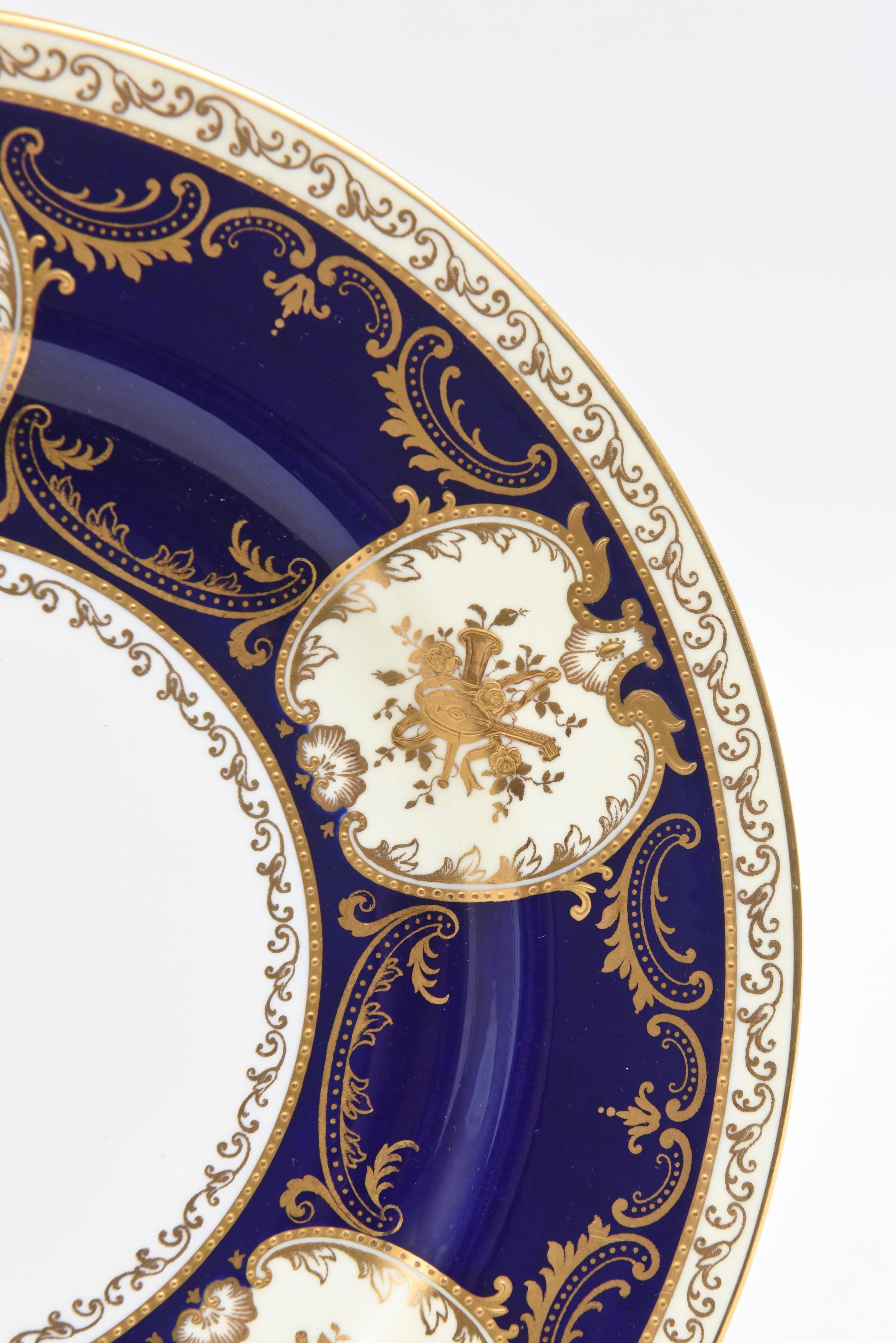 A rare and wonderful custom set of 11 plates from Copeland Spode England. Rich Cobalt Blue Extended Collars featuring raised gilt encrusted cartouches of musical instruments. Custom ordered through the fine gilded age Philadelphia firm of J. E.