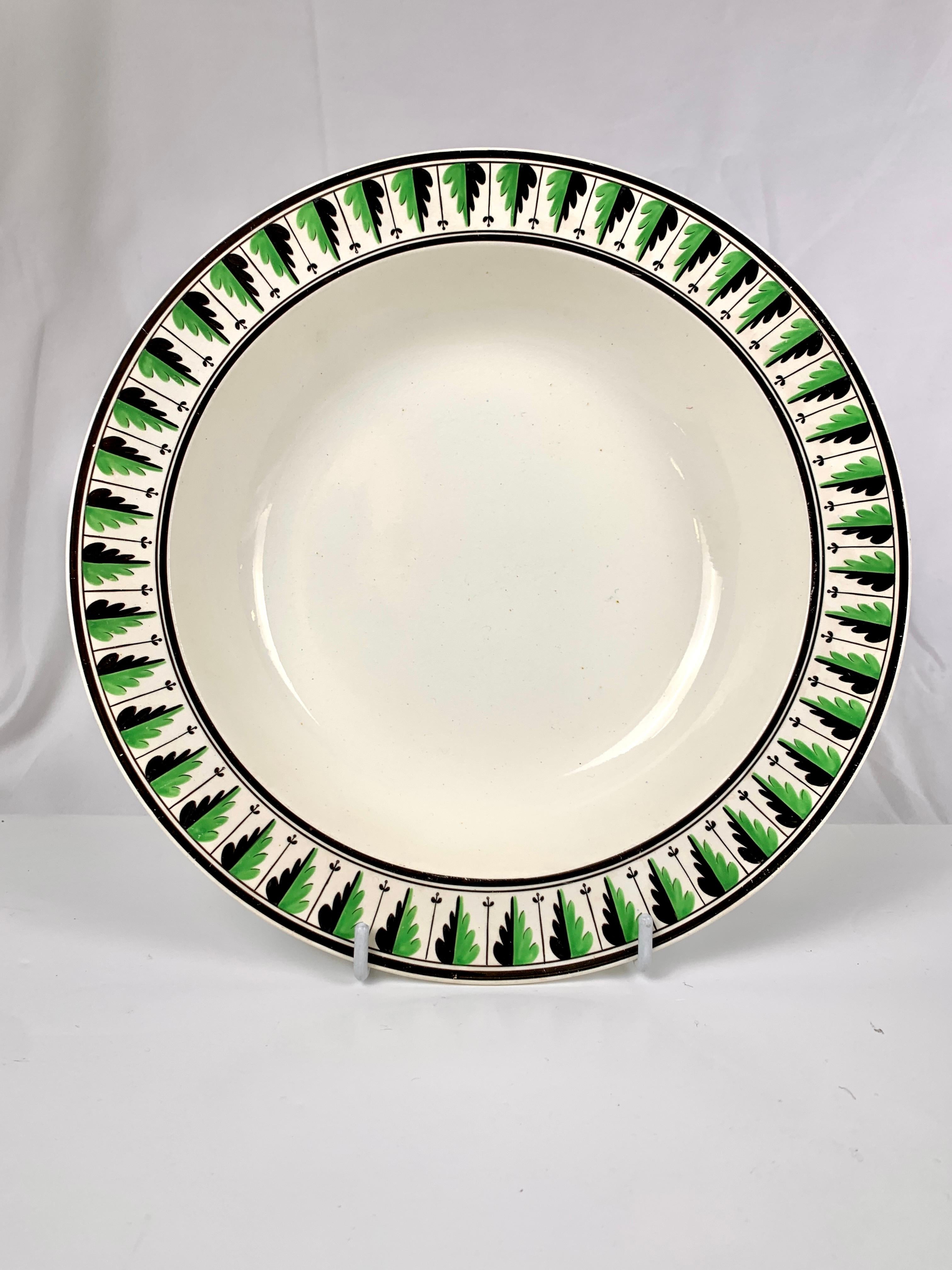 This elegant set of eleven large creamware soup dishes from Spode, circa 1820, is a beautiful example of English neoclassical style. 
The acanthus leaf border, painted with bright enamels with each leaf divided down the middle, painted half green